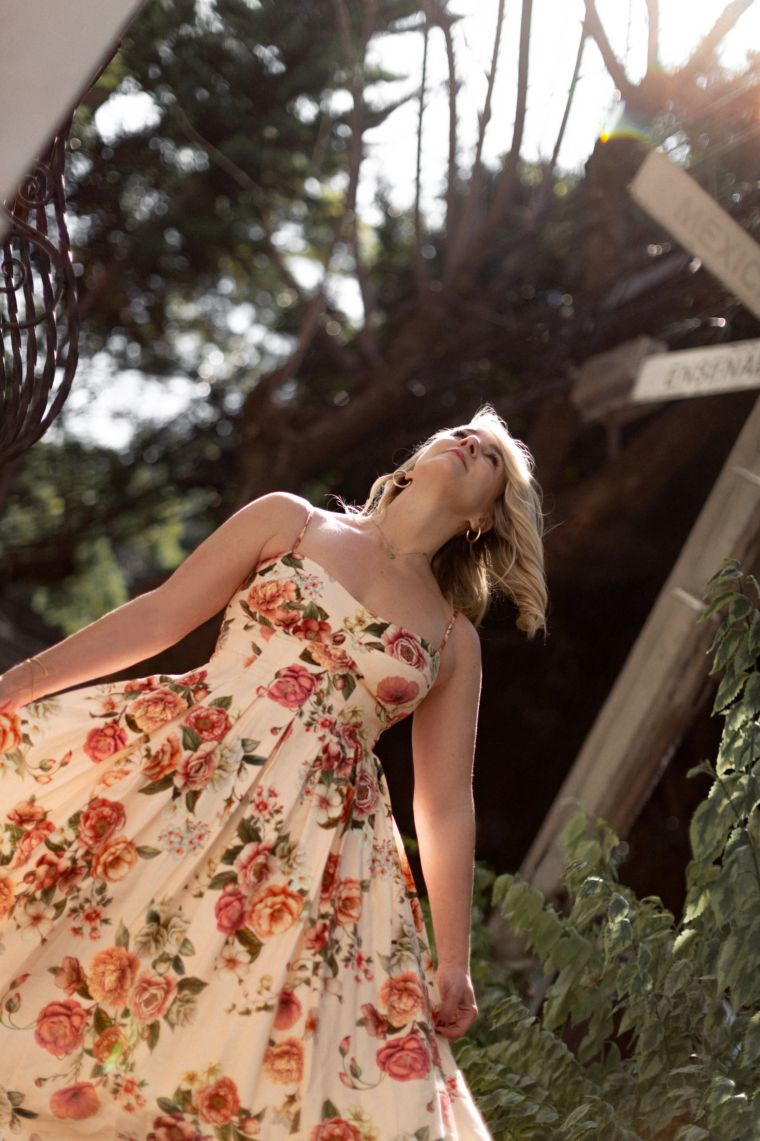 Jessica Hetherington, The Pelvic Pain Mentor in a floral dress standing outdoors with sunlight in the background.