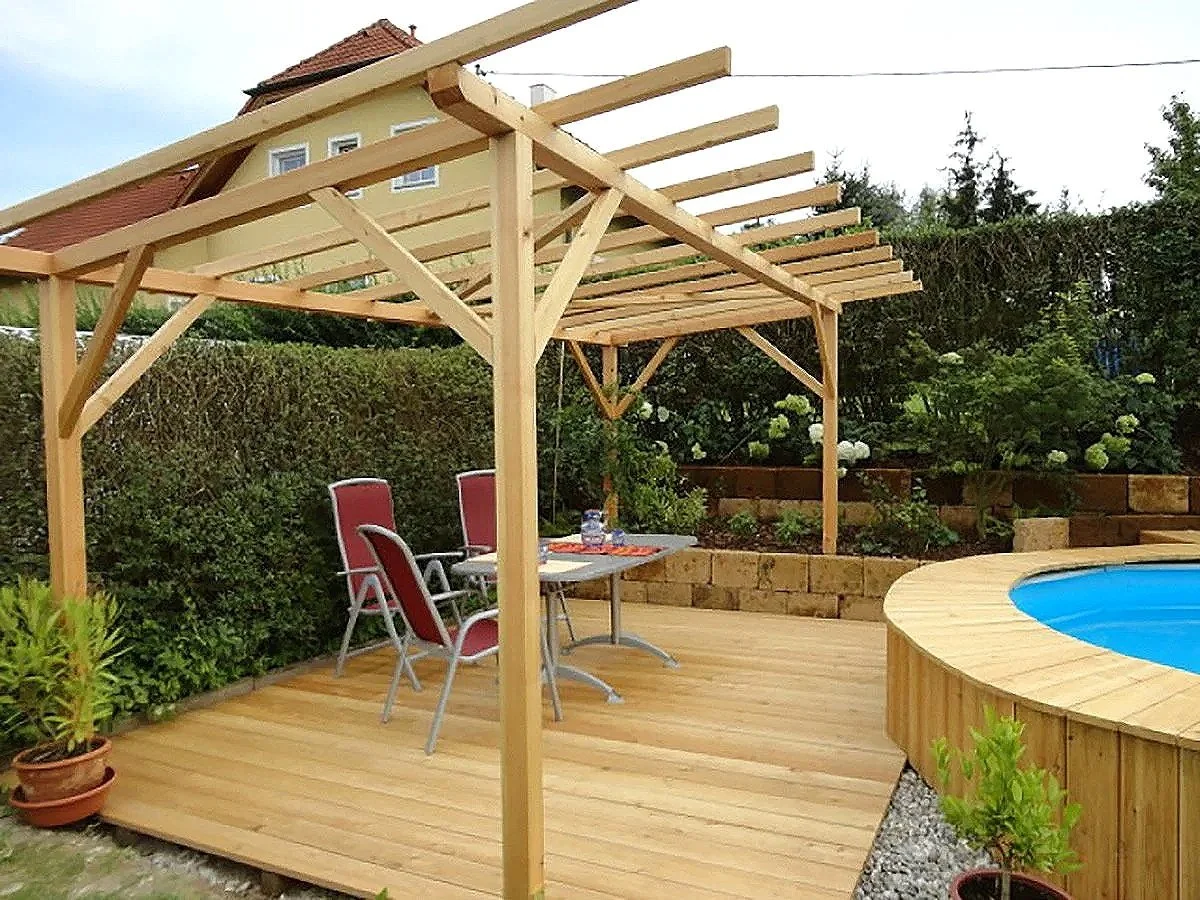 Garten mit hölzerner Terrasse, Pool, Esstisch, Stühle und Holzpergola.