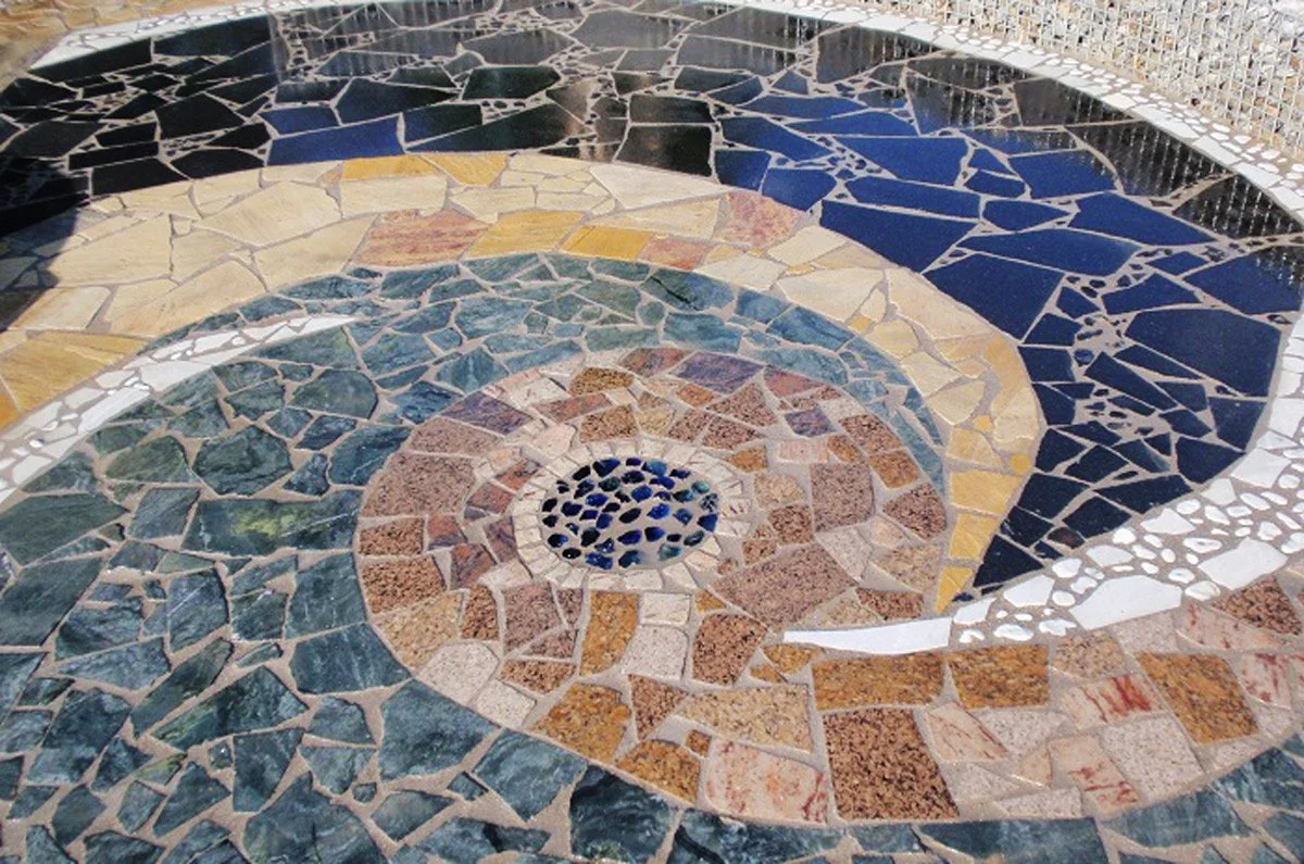 Mosaikboden mit spiralförmigem Muster aus verschiedenen bunten Steinen.