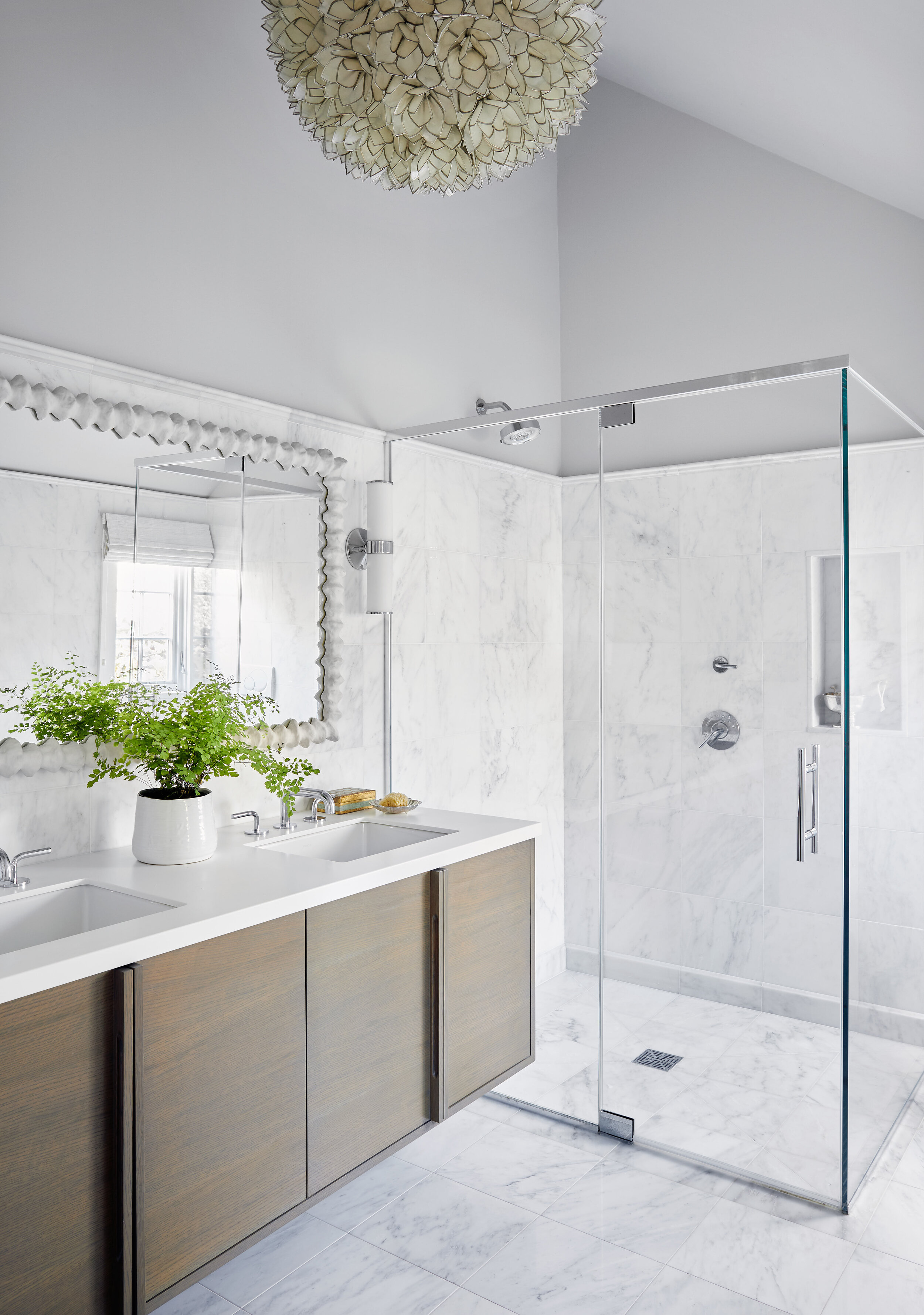 Modern bathroom with a double sink vanity, large mirror, and a glass-enclosed shower with marble walls and floor.