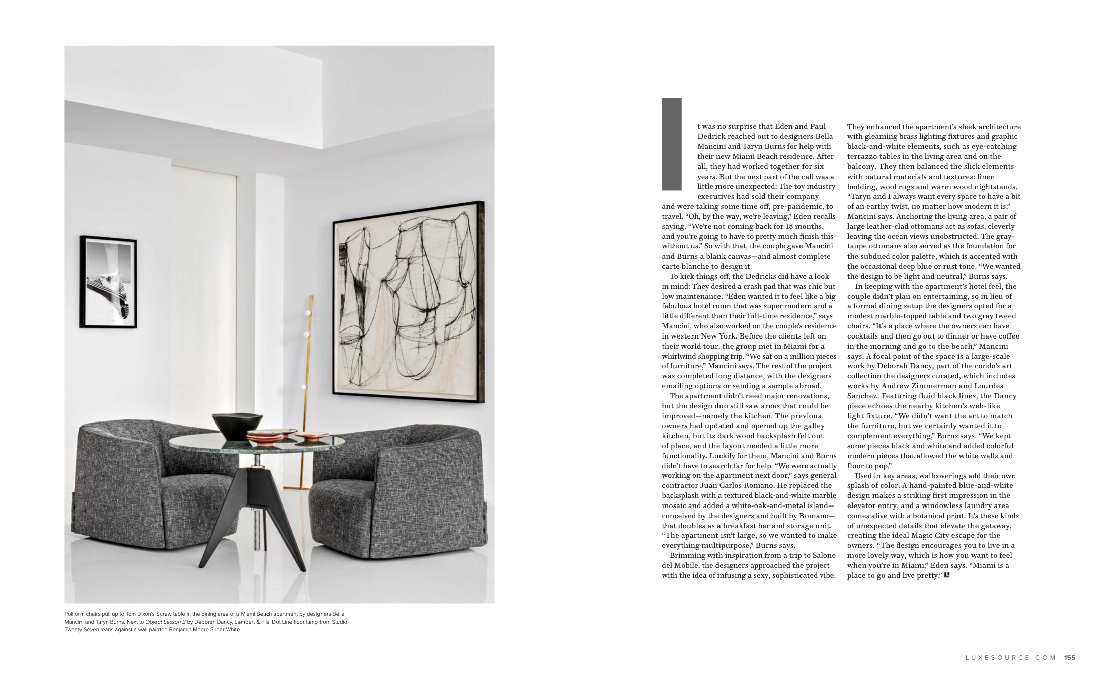 Interior of a modern living room with a round black table, four gray upholstered chairs, and wall art including an abstract black and white sketch.