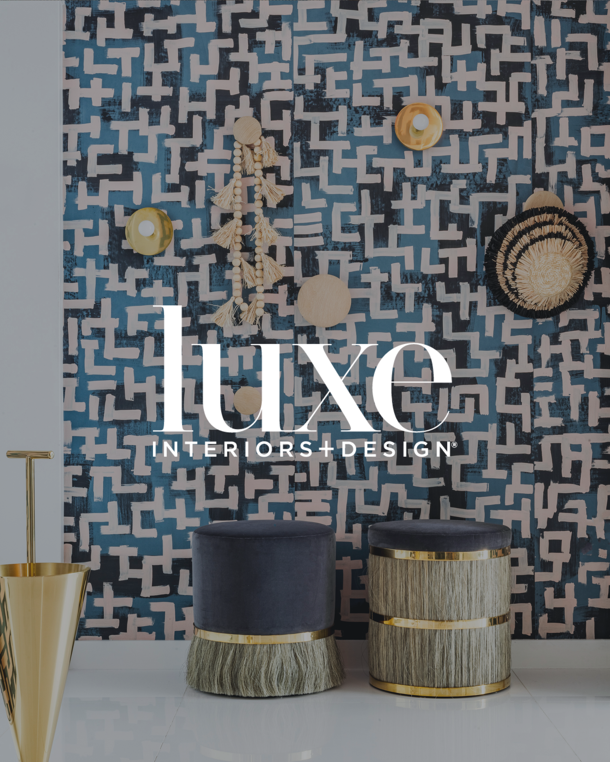 Decorative modern interior with a geometric blue and white wall, two dark velvet stools with gold band accents, and a shiny gold cone-shaped side table.