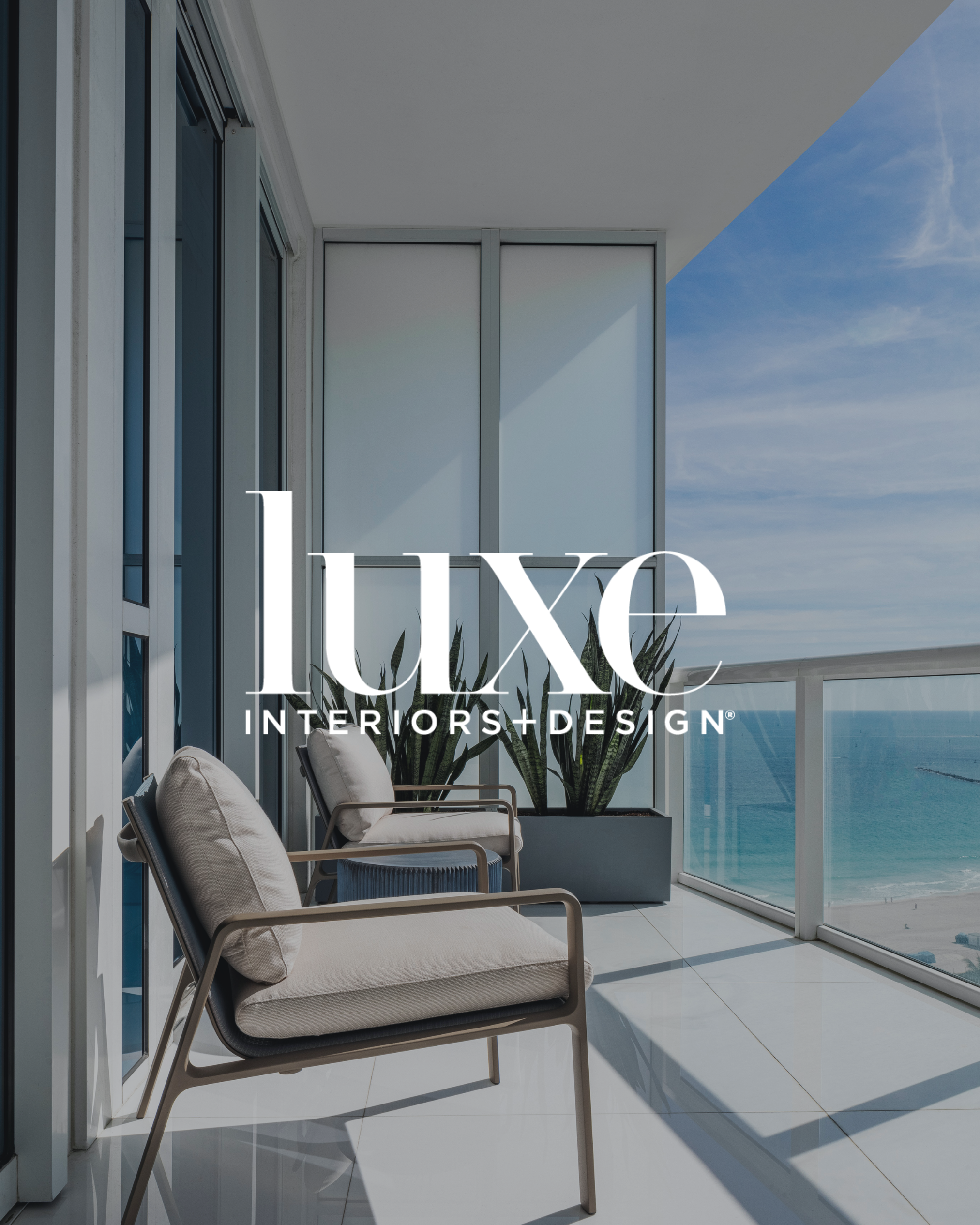 Balcony with two modern chairs, potted plants, glass railing, and ocean view, with the text "Luxe Interiors + Design" overlaid.
