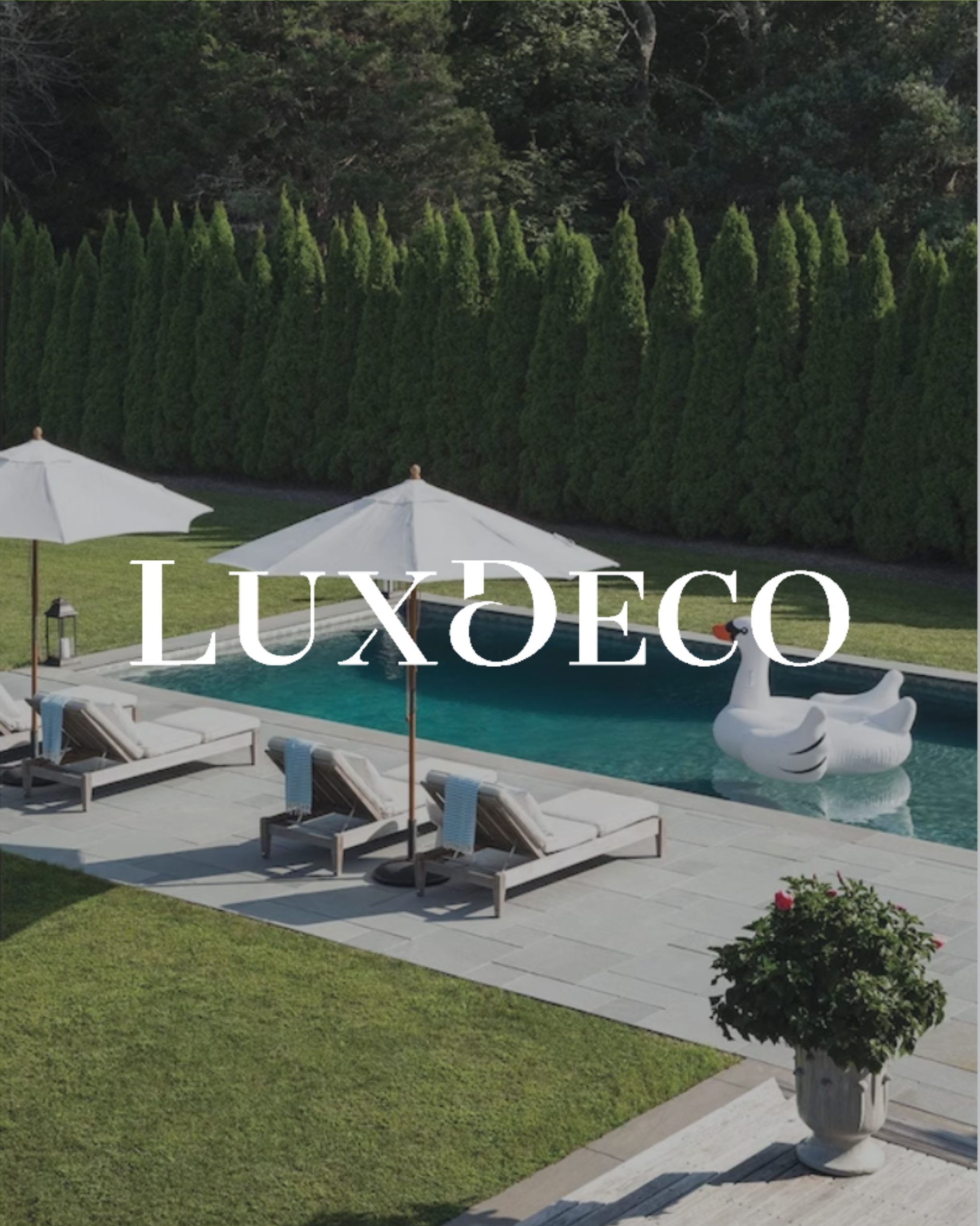 Luxury backyard with a swimming pool, white lounge chairs, umbrellas, a decorative paddle boat, and a row of tall green trees in the background.