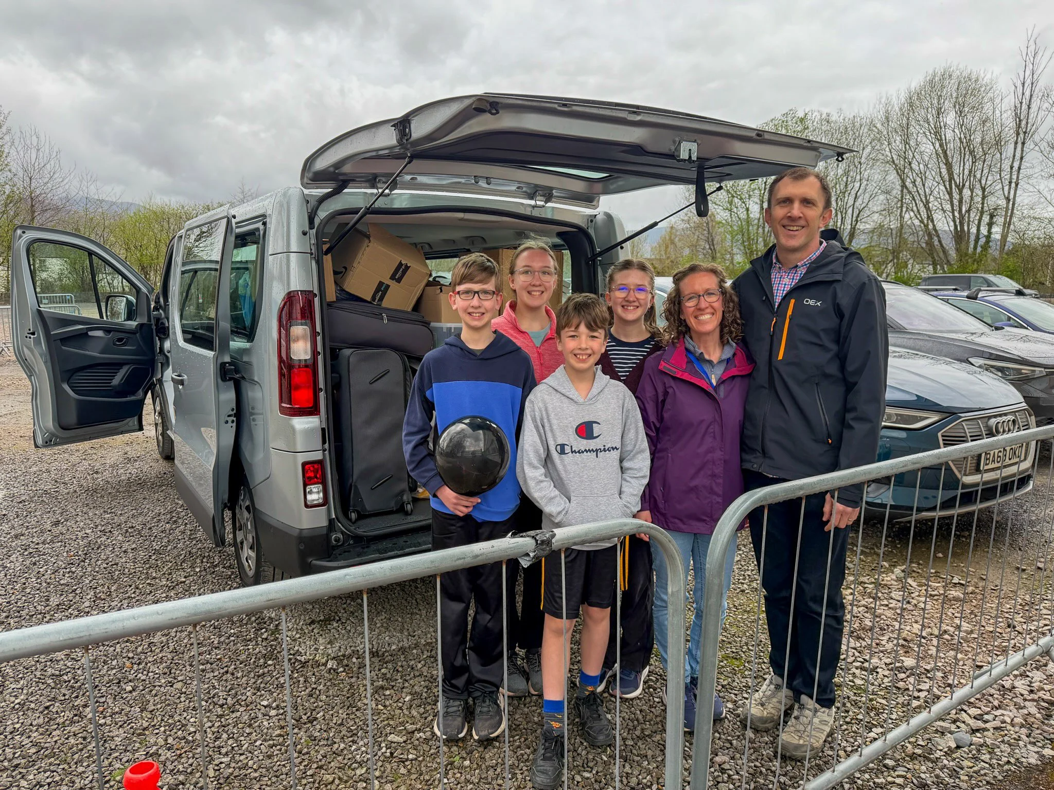 A man and four children smiling in front of a historic cathedral.