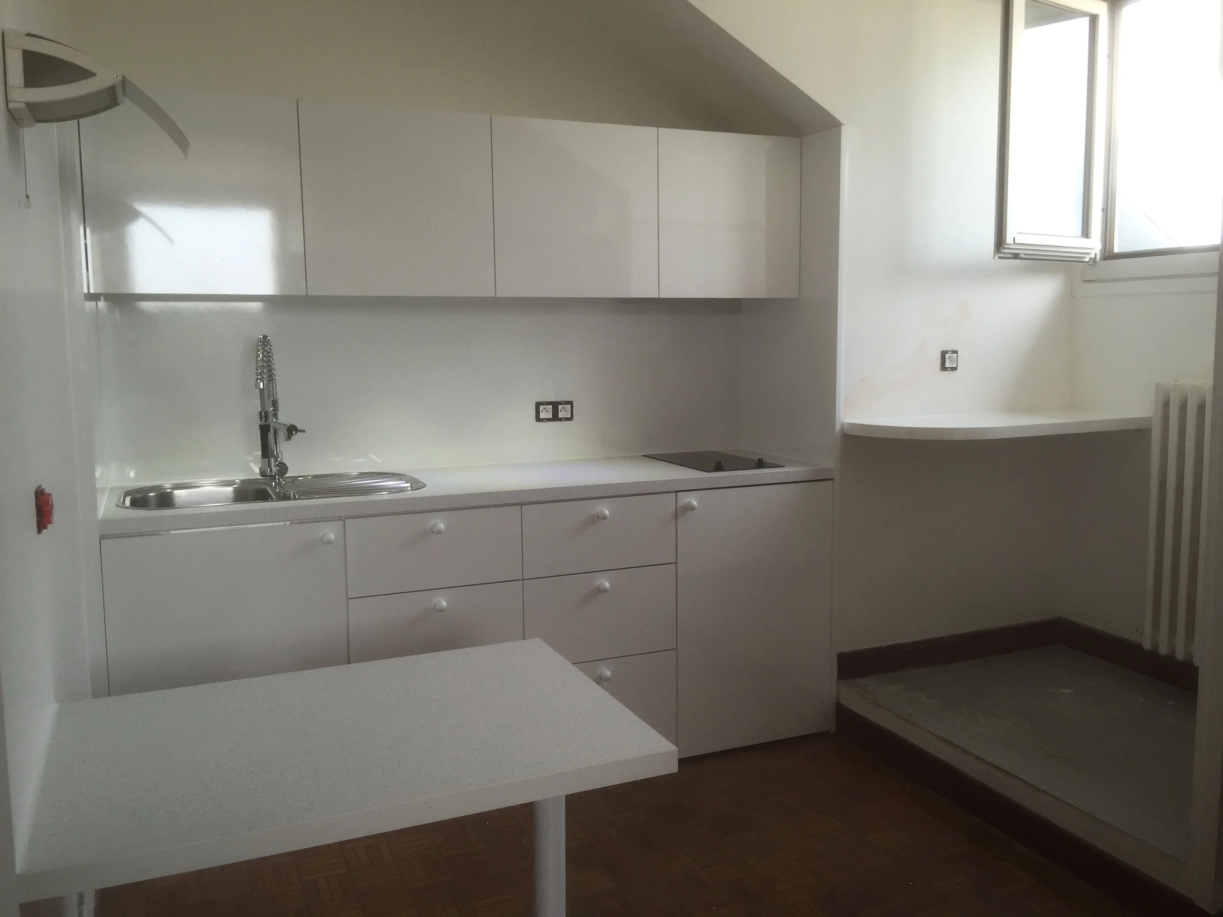 A kitchen with white cabinets, a sink, and a window allowing natural light.