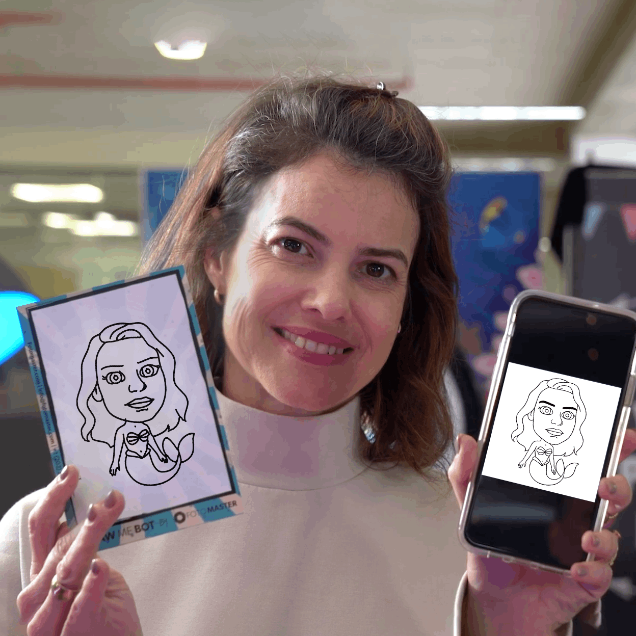 A woman with long black hair smiling and holding a white card with a caricature drawing of woman's face drawn by Draw Me Bot machine