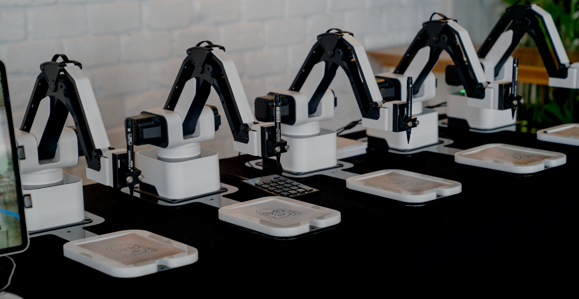 Multiple robotic arms positioned over platforms at a technology demonstration or research facility.