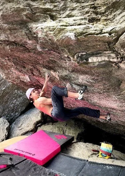 Grimpeur sur un bloc en dévers au-dessus d'un crash pad / Climber on an overhanging boulder above a crash pad, best chalk from Canada