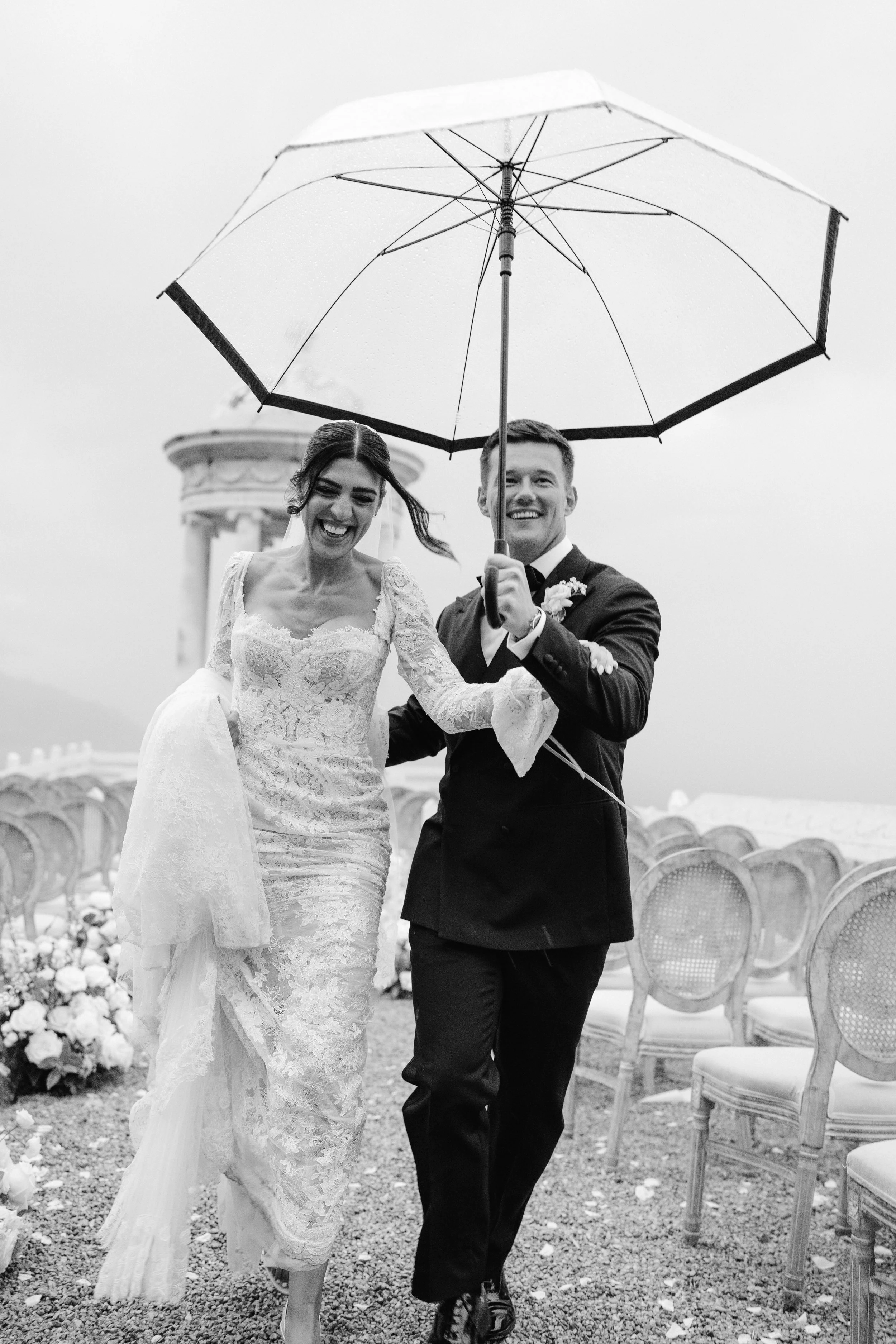Happy bride and groom walking together with umbrella on outdoor wedding ceremony day at Son Marroig with Laura Shuckburgh