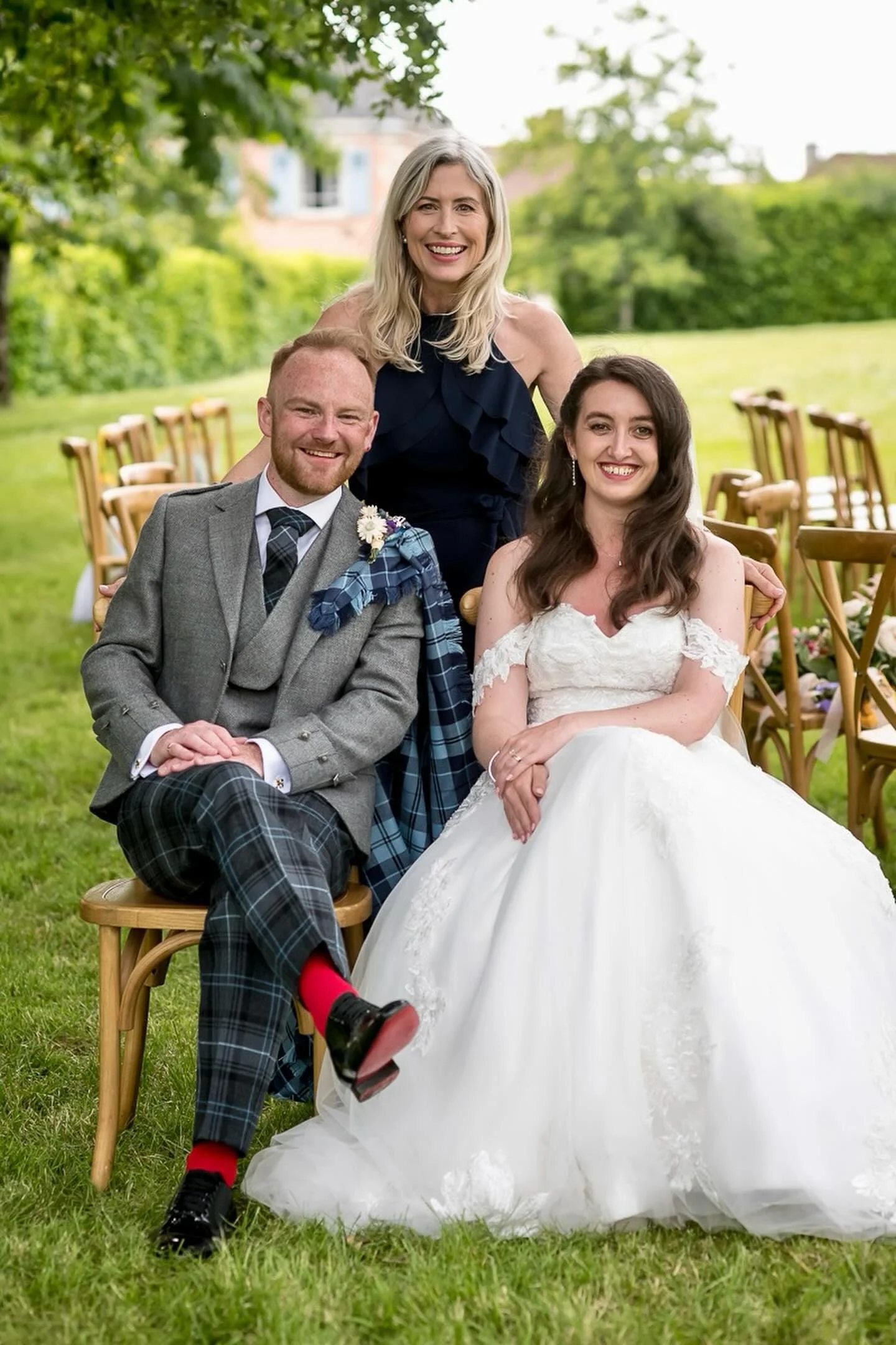 A Scottish wedding at Chateau de Bourneau dressed formally for a wedding, with the Chateau Celebrant smiling behind them.