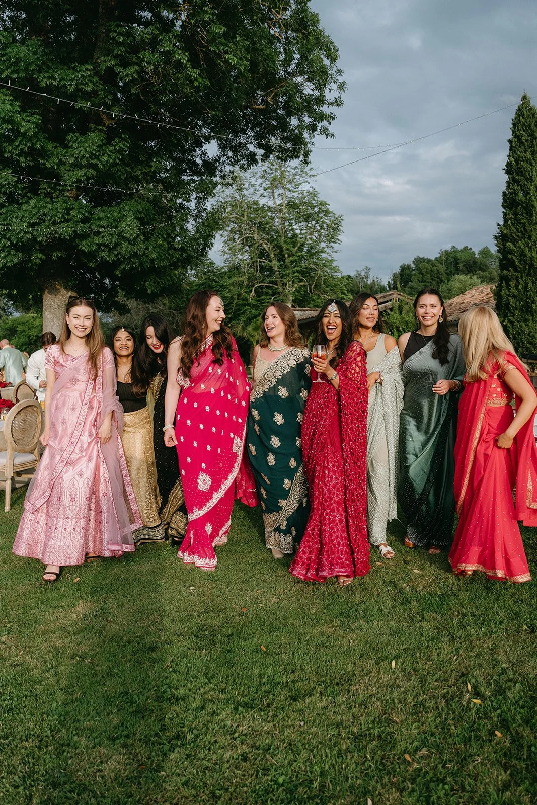 Group of women in colorful traditional dresses standing on grass at Chateau de Garde