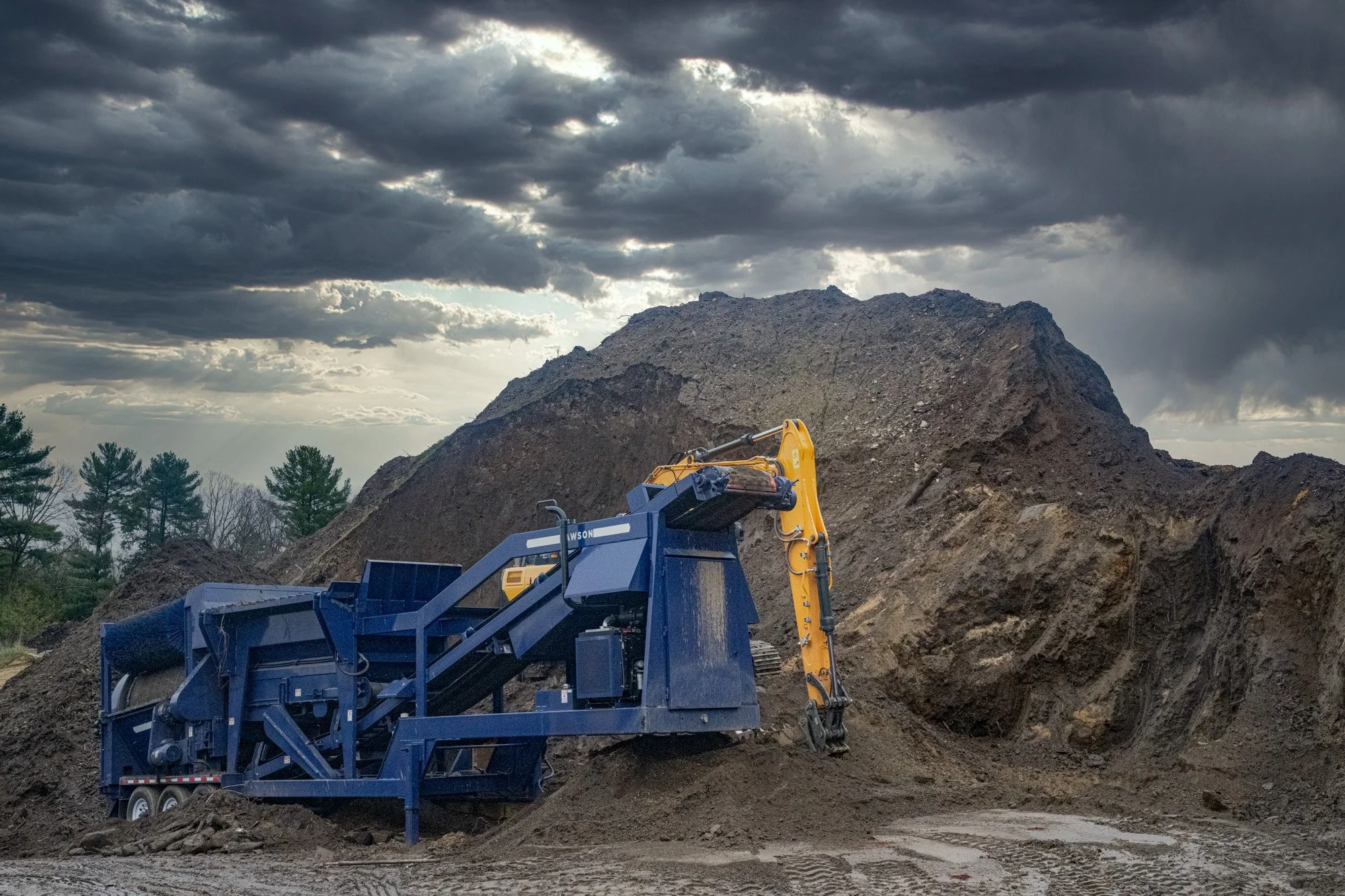 Loam pile with screener and excavator