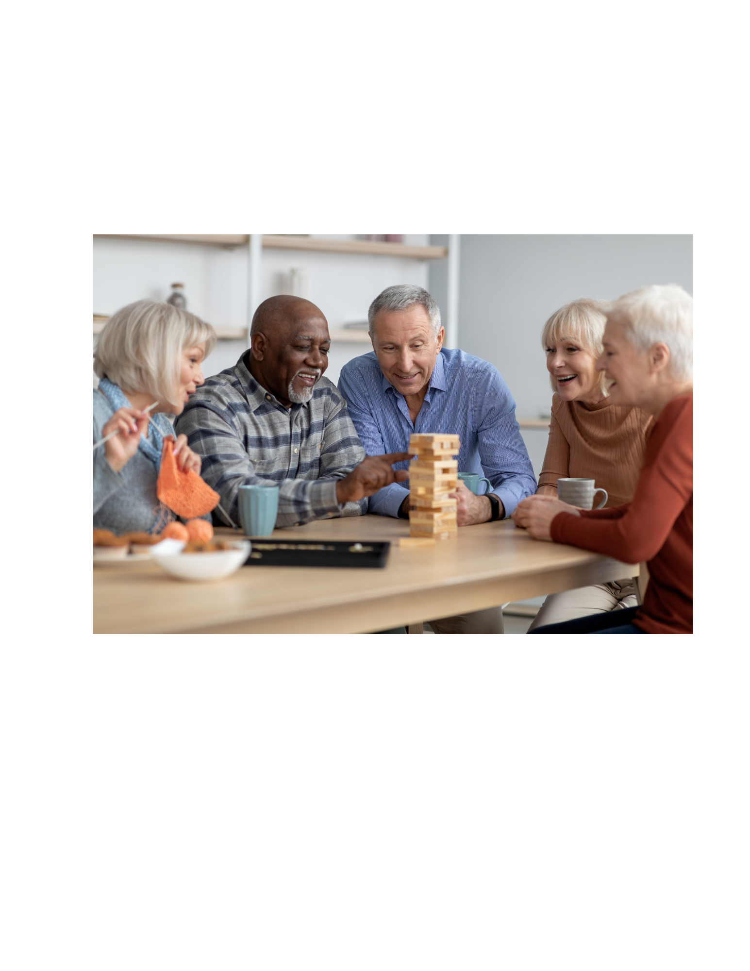 Group of five elderly friends playing Jenga and enjoying each other's company at a table with snacks and drinks.