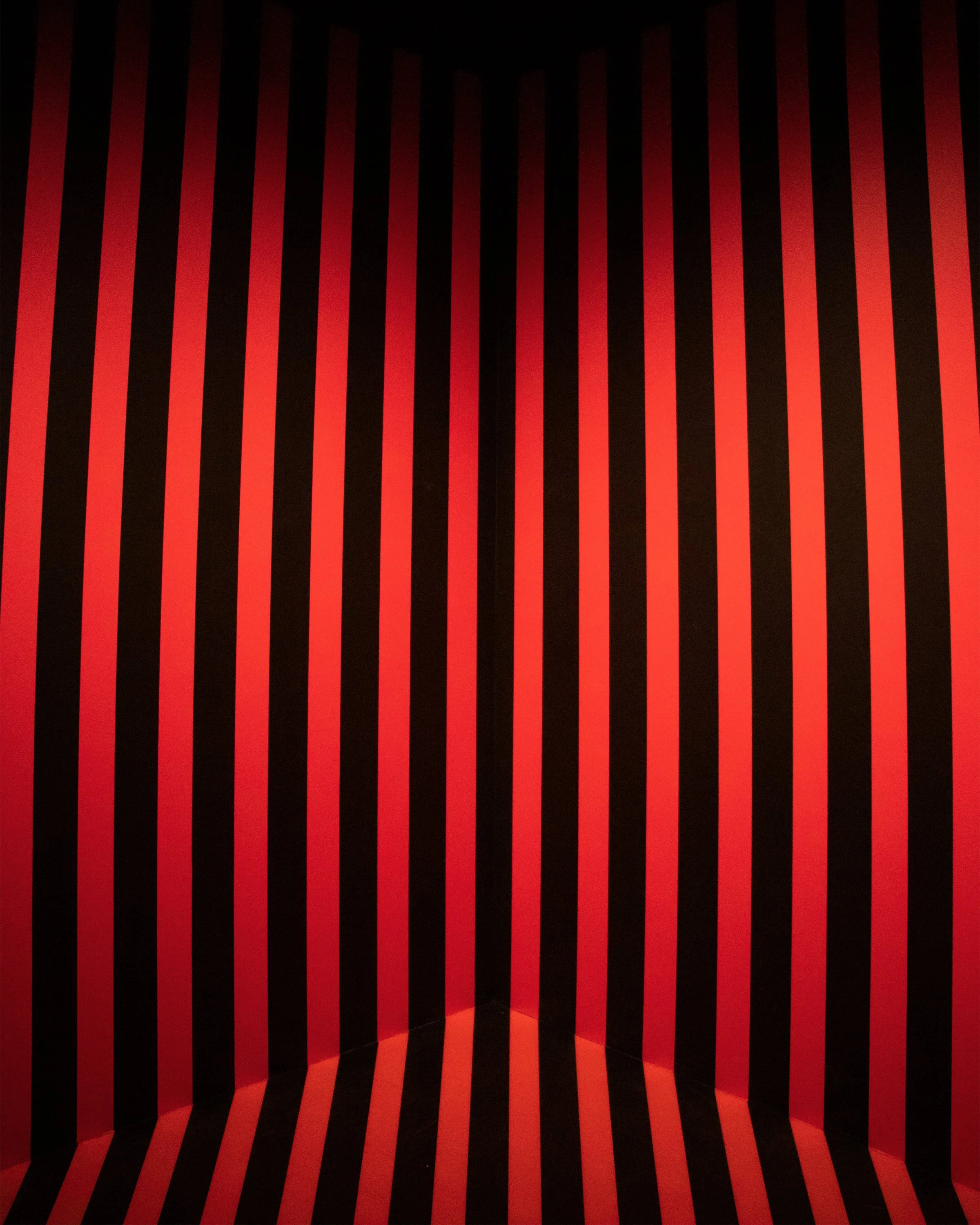 Red and black striped room with vertical and diagonal stripes on walls and floor, creating a geometric pattern.