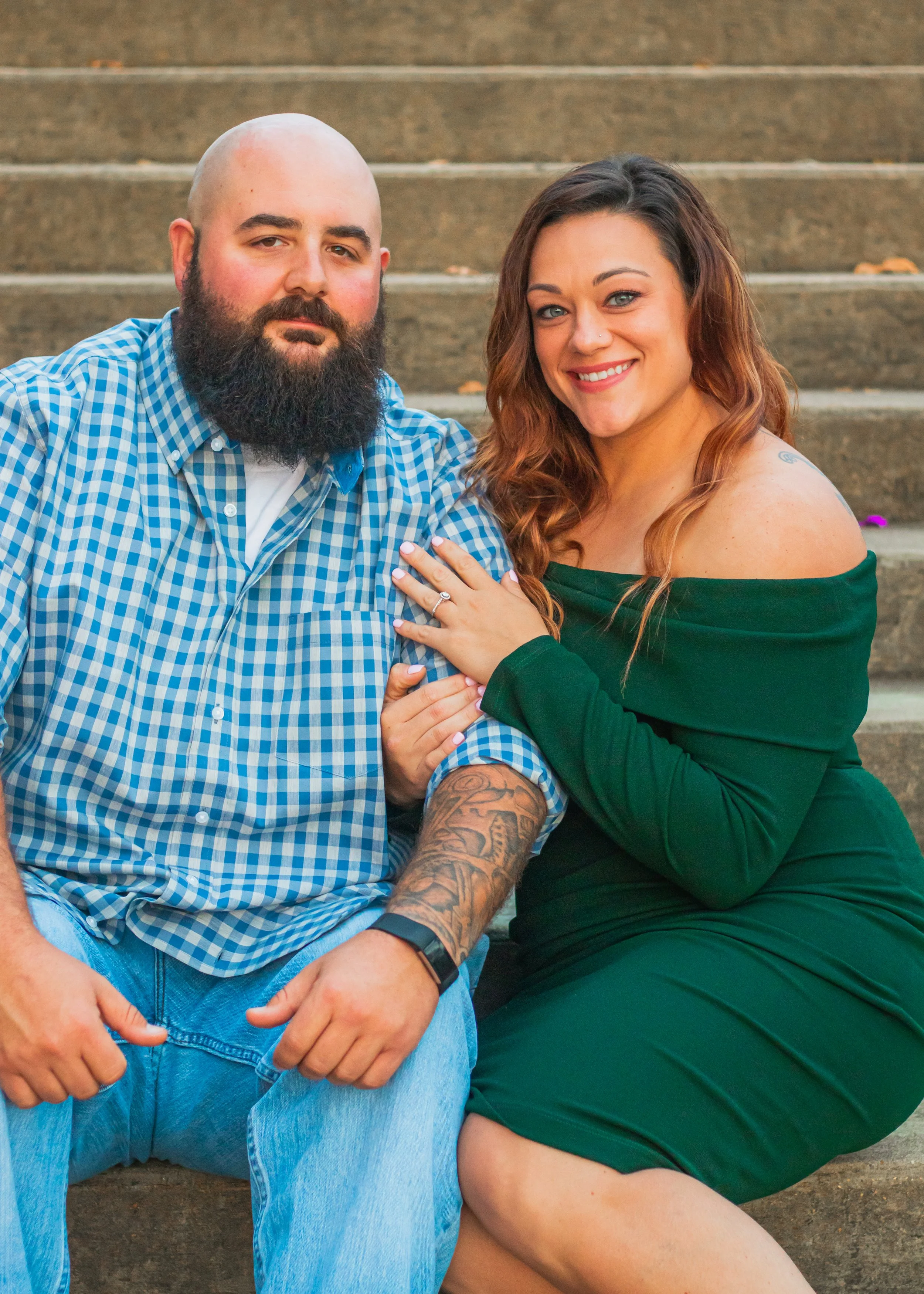 A man and woman sitting on outdoor steps, smiling and facing the camera. 