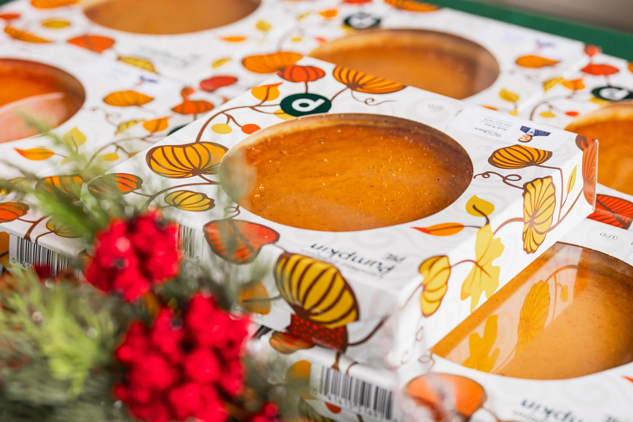 Several pumpkin-shaped desserts in white boxes decorated with orange and yellow leaves and butterflies.