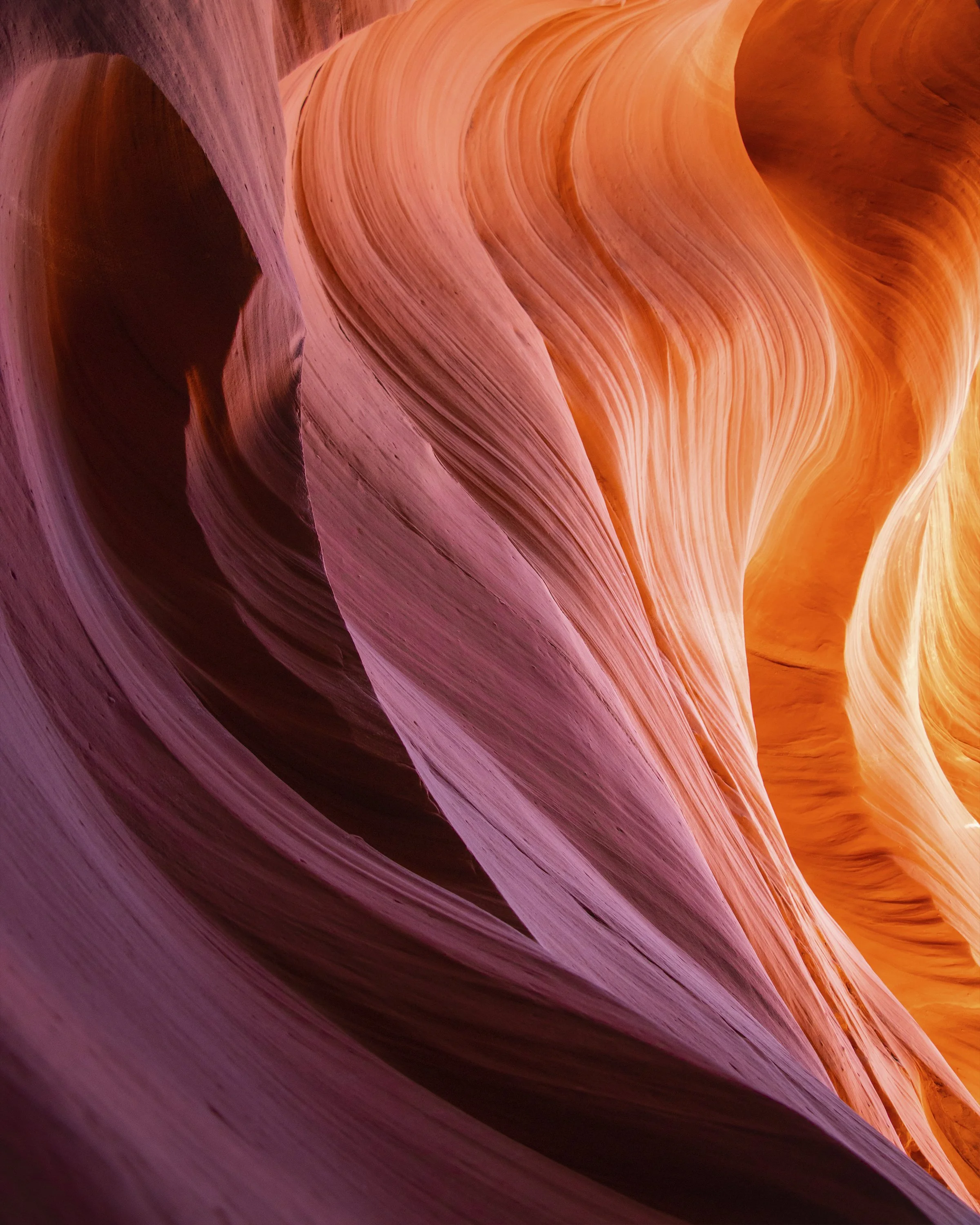 Close-up view of canyon walls with smooth, curved sandstone layers in pink, orange, and purple hues. Lower antelope slot canyon Arizona. 