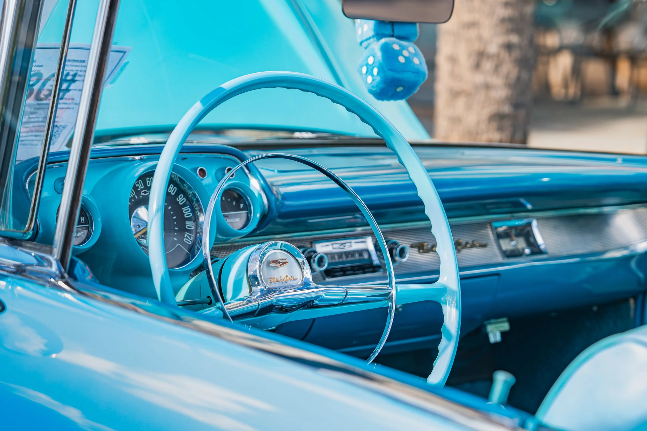 Interior of a vintage Chevrolet Bel Air car in light blue, showing the steering wheel, dashboard, and vintage gauges.