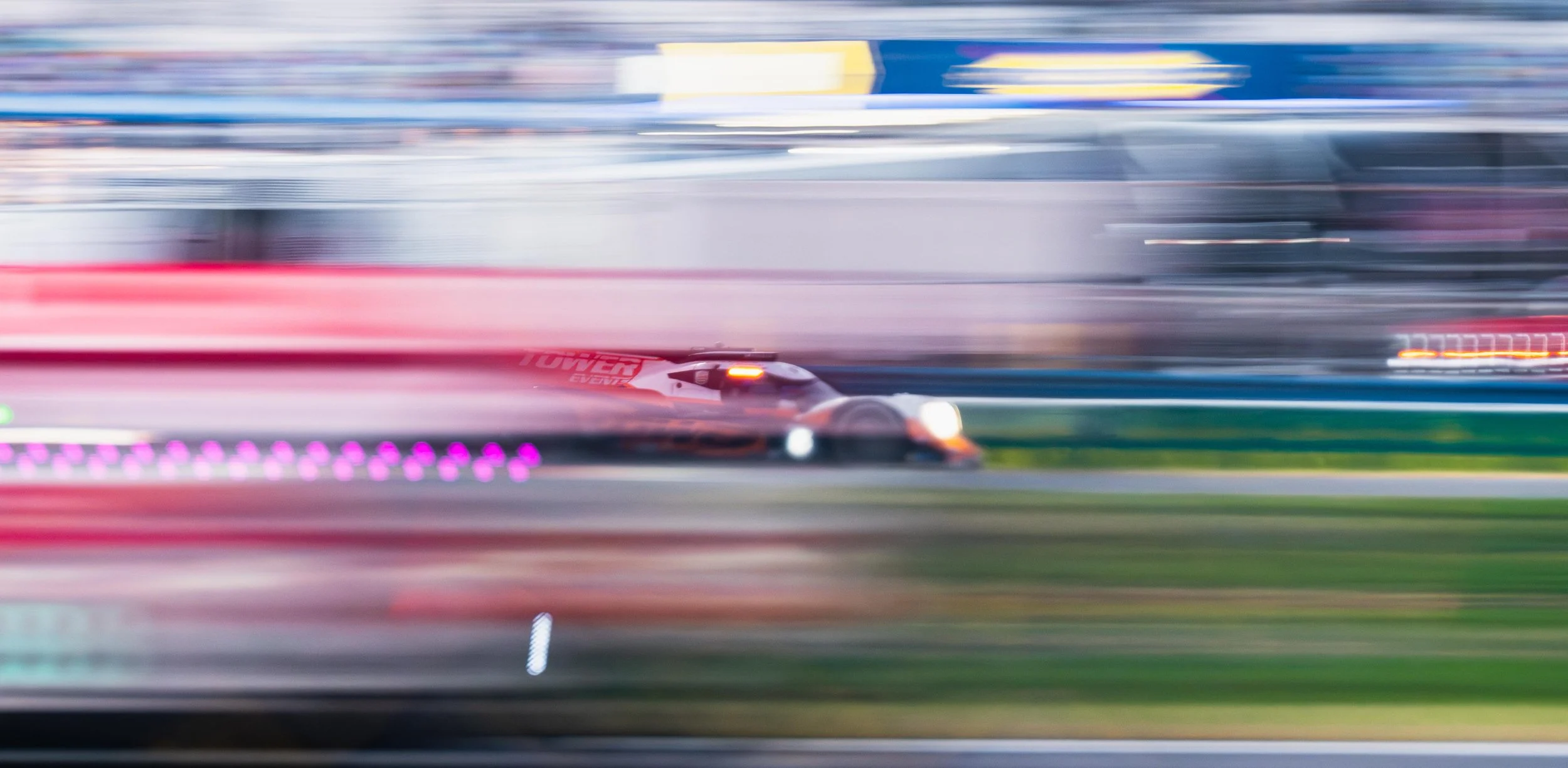A race car speeding on a track with motion blur in the background and foreground.