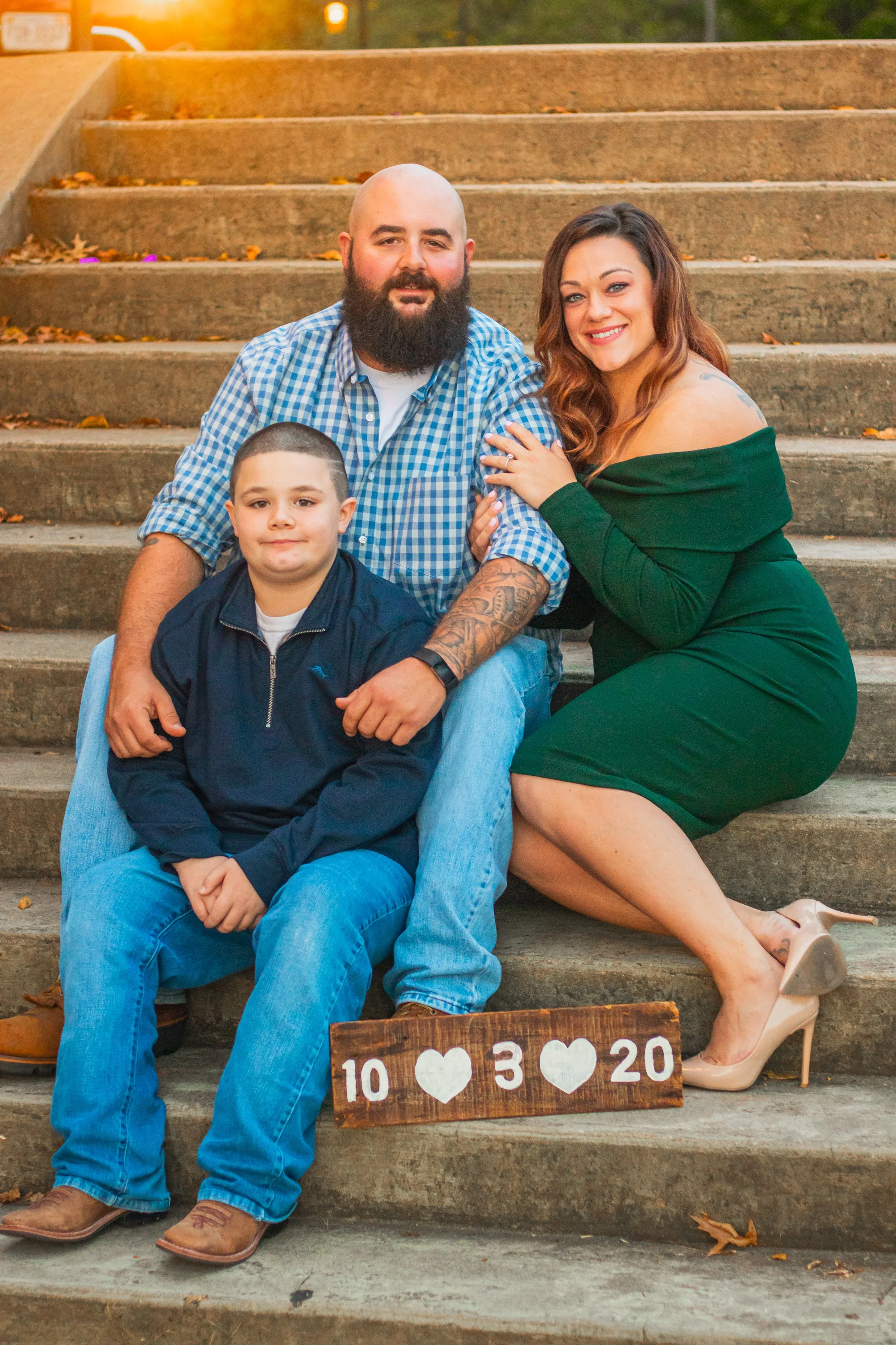 A family of three sitting on outdoor stairs, with a man, woman, and young boy. 