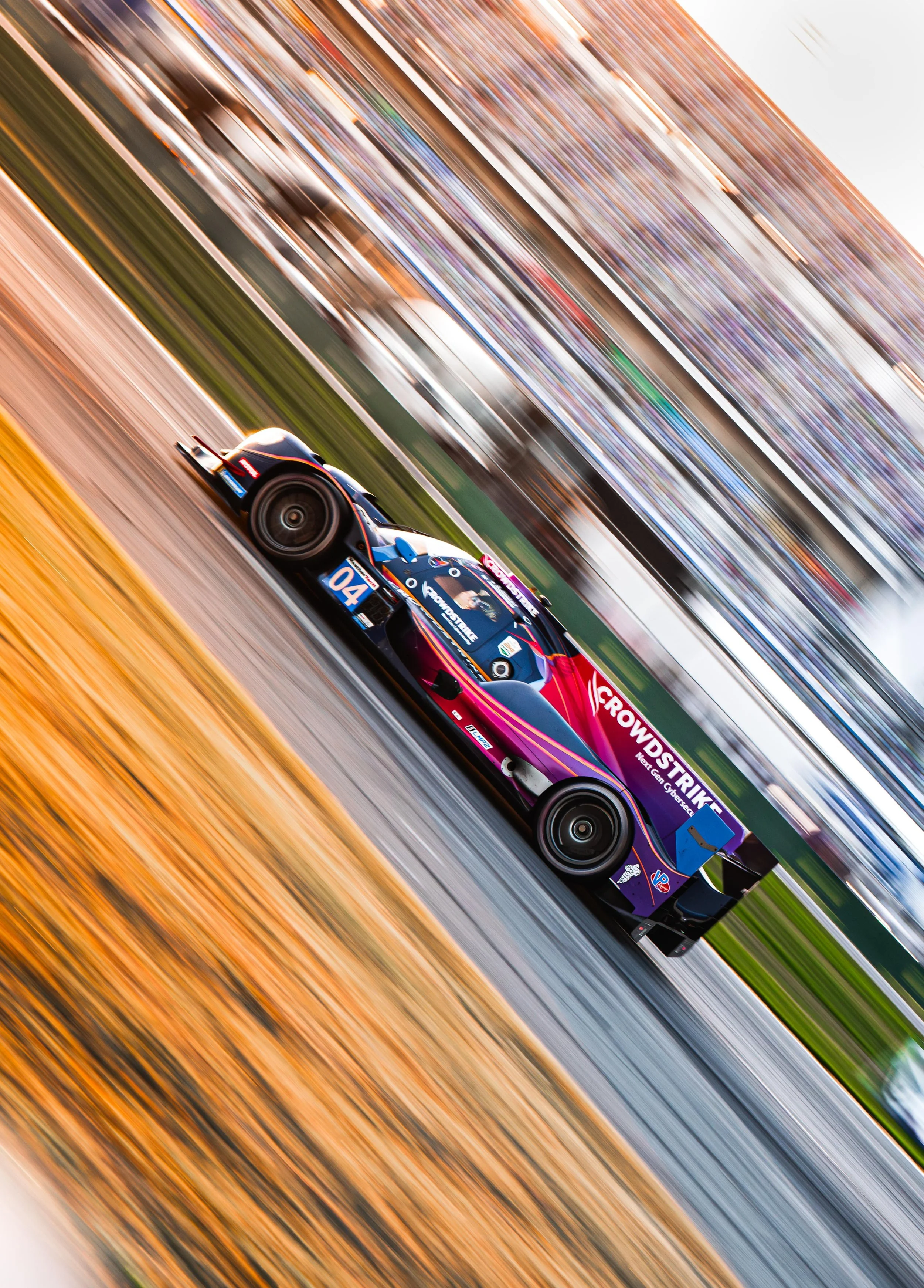 A race car speeding on a track with blurred crowds in the background.