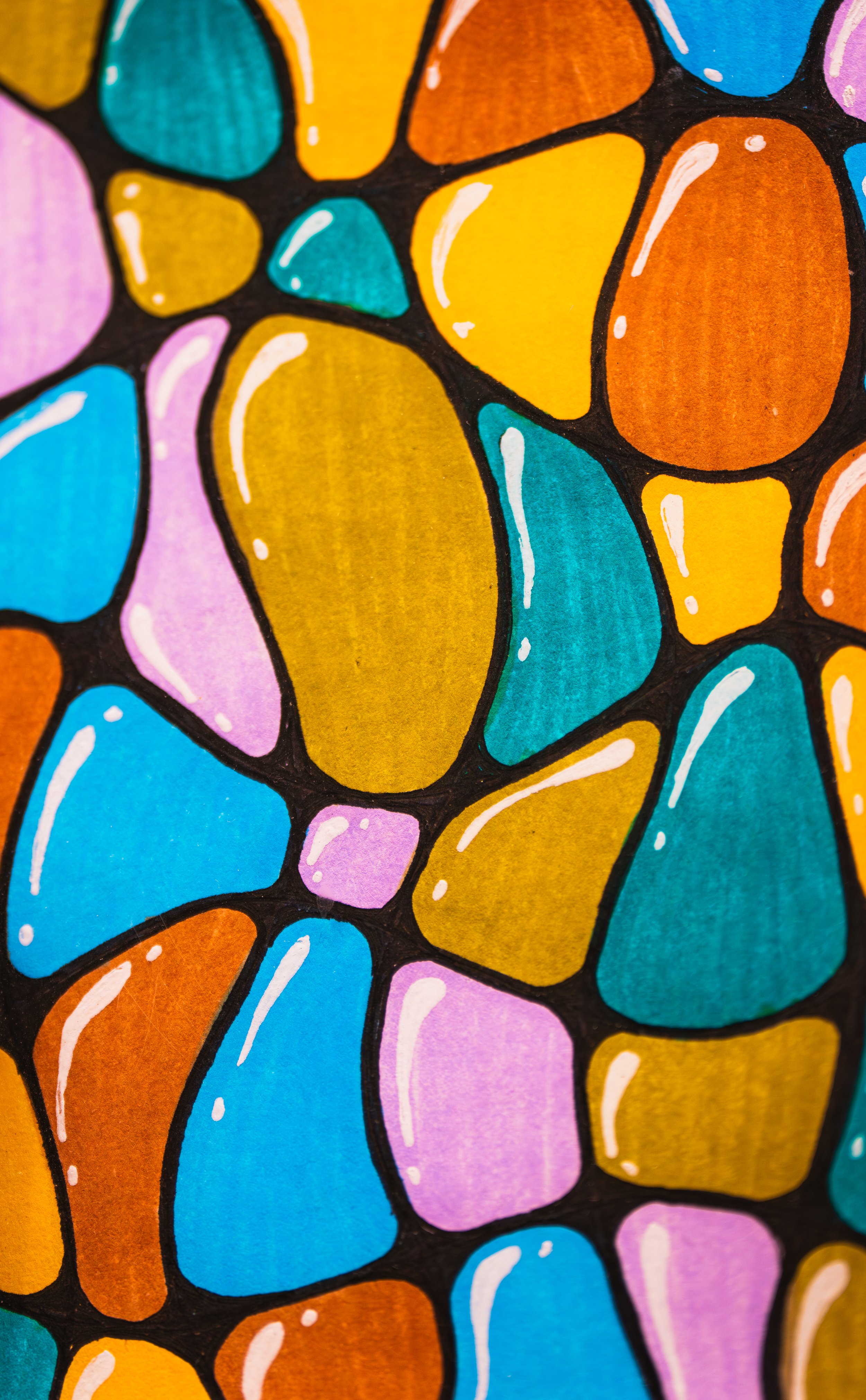 Close-up of a colorful abstract drawing resembling stones or pebbles in orange, yellow, blue, pink, and purple, outlined in black with white highlights.