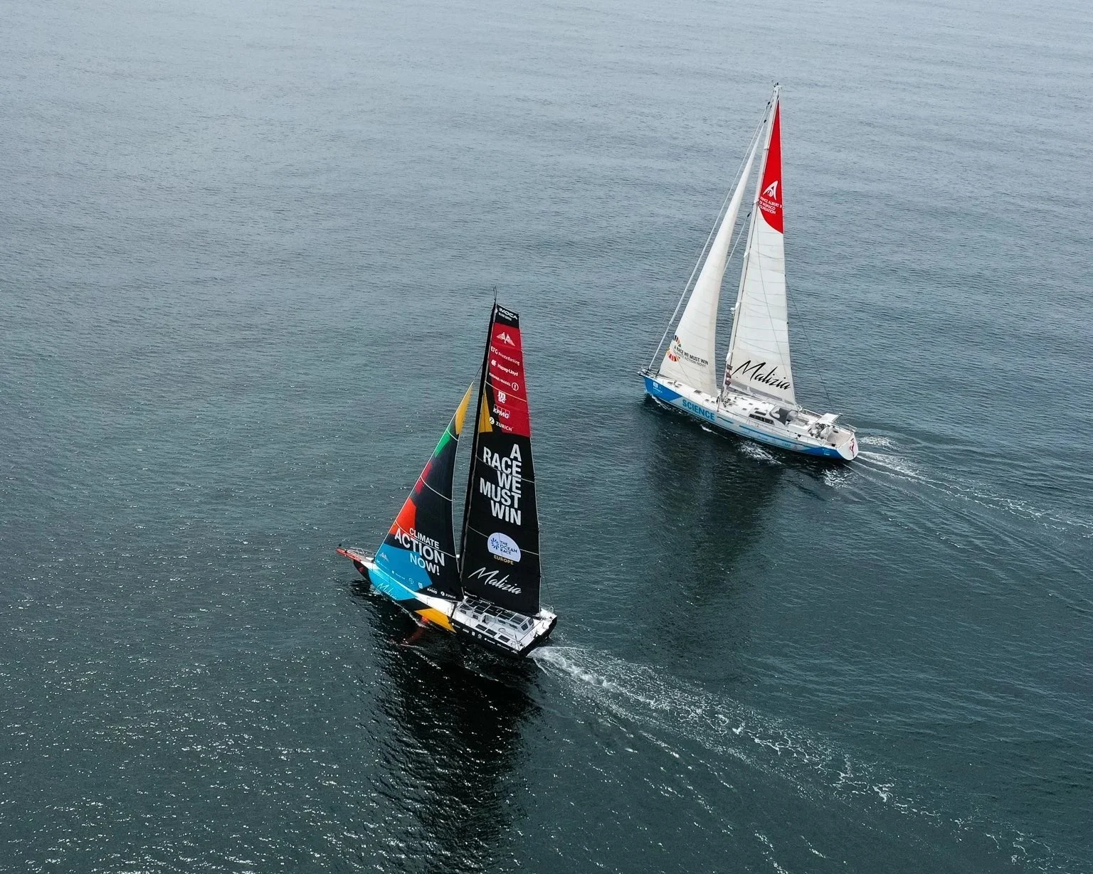Malizia Seaexplorer racing IMOCA sailing next to Malizia Explorer science research vessel in Lorient.