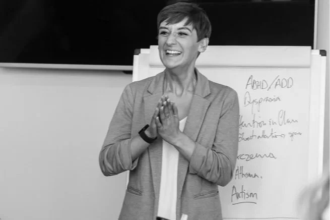 Light wooden desk with a lined notebook, a pen, and a cup of coffee, with sunlight creating shadows.