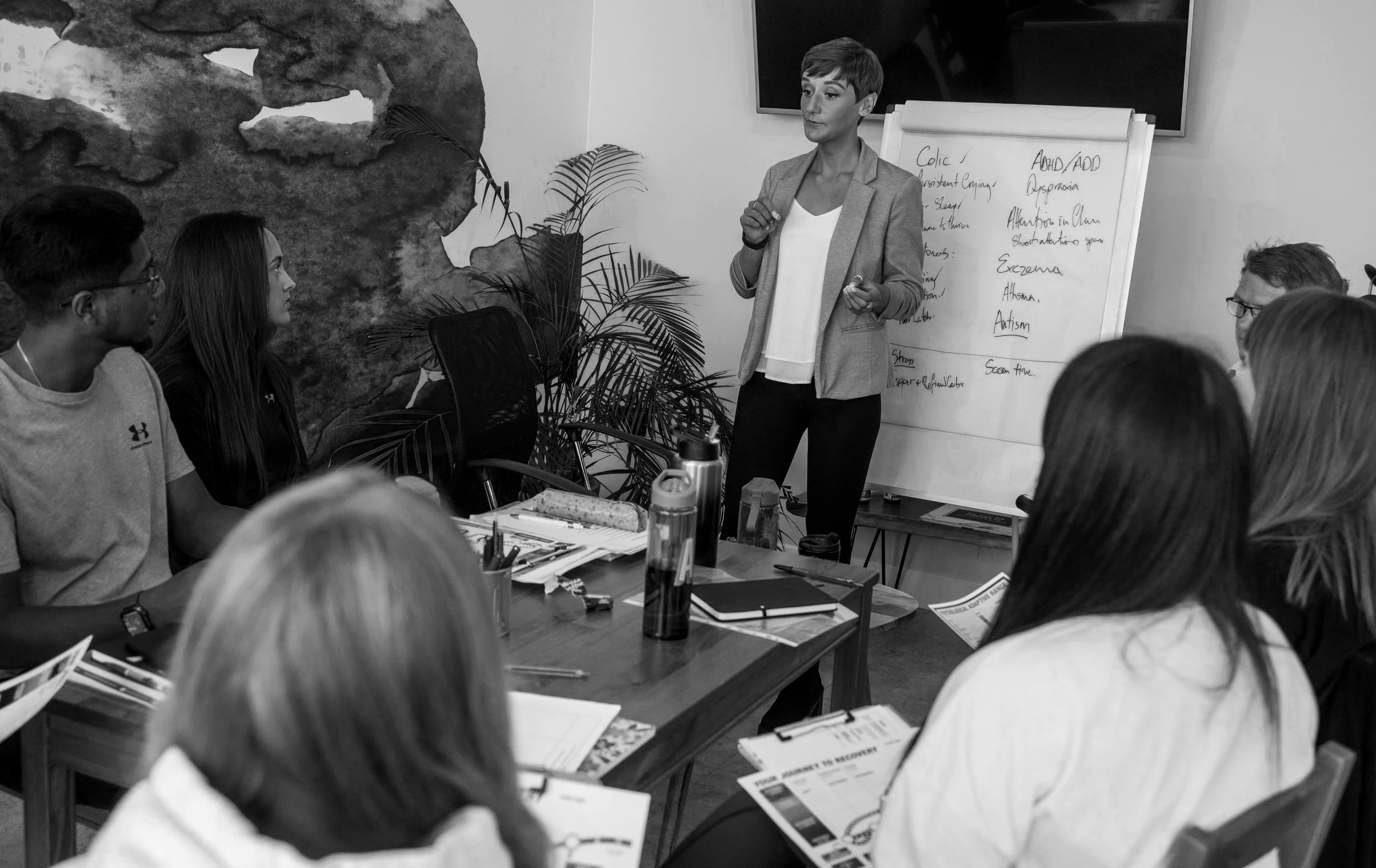 Six hands making overlapping heart shapes with their fingers against a bright sky background.