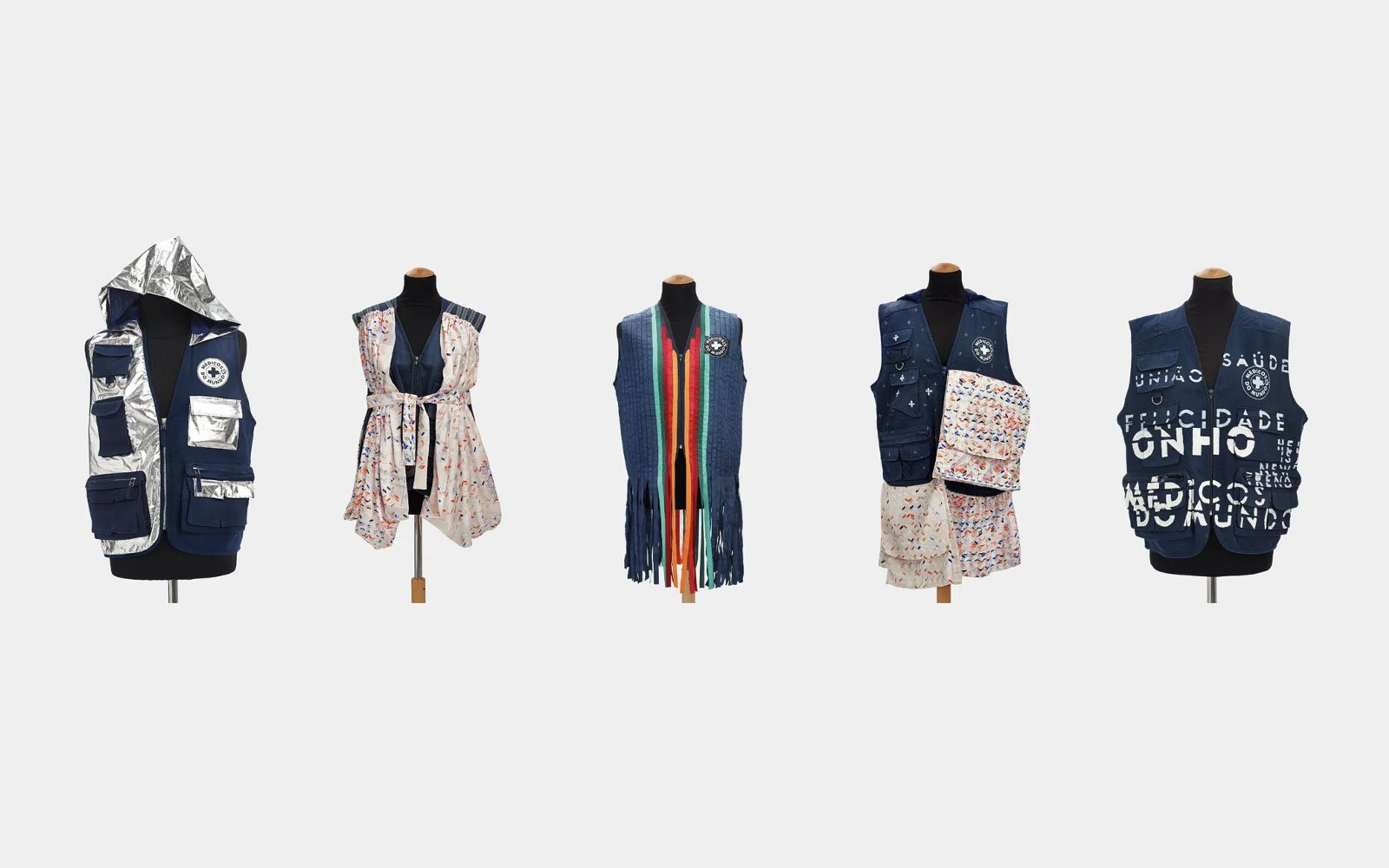 Five mannequins dressed in colorful vests and layered clothing, with distinct patterns and accessories, displayed in a row against a plain background.