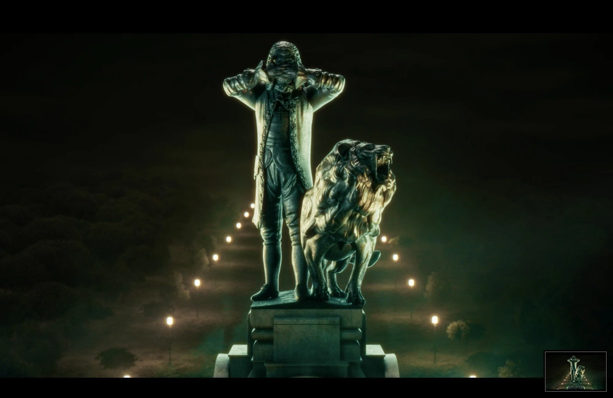 Statue of a man and a lion on a pedestal, with a dark background and illuminated pathway lights.