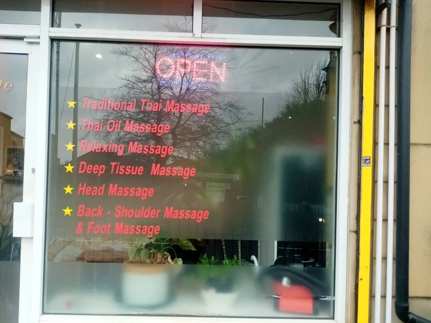 Sign with a list of massage services, including Traditional Thai Massage, Thai Oil Massage, Relaxing Massage, Deep Tissue Massage, Head Massage, and Back, Shoulder, & Foot Massage, with an illuminated "OPEN" sign at the top.