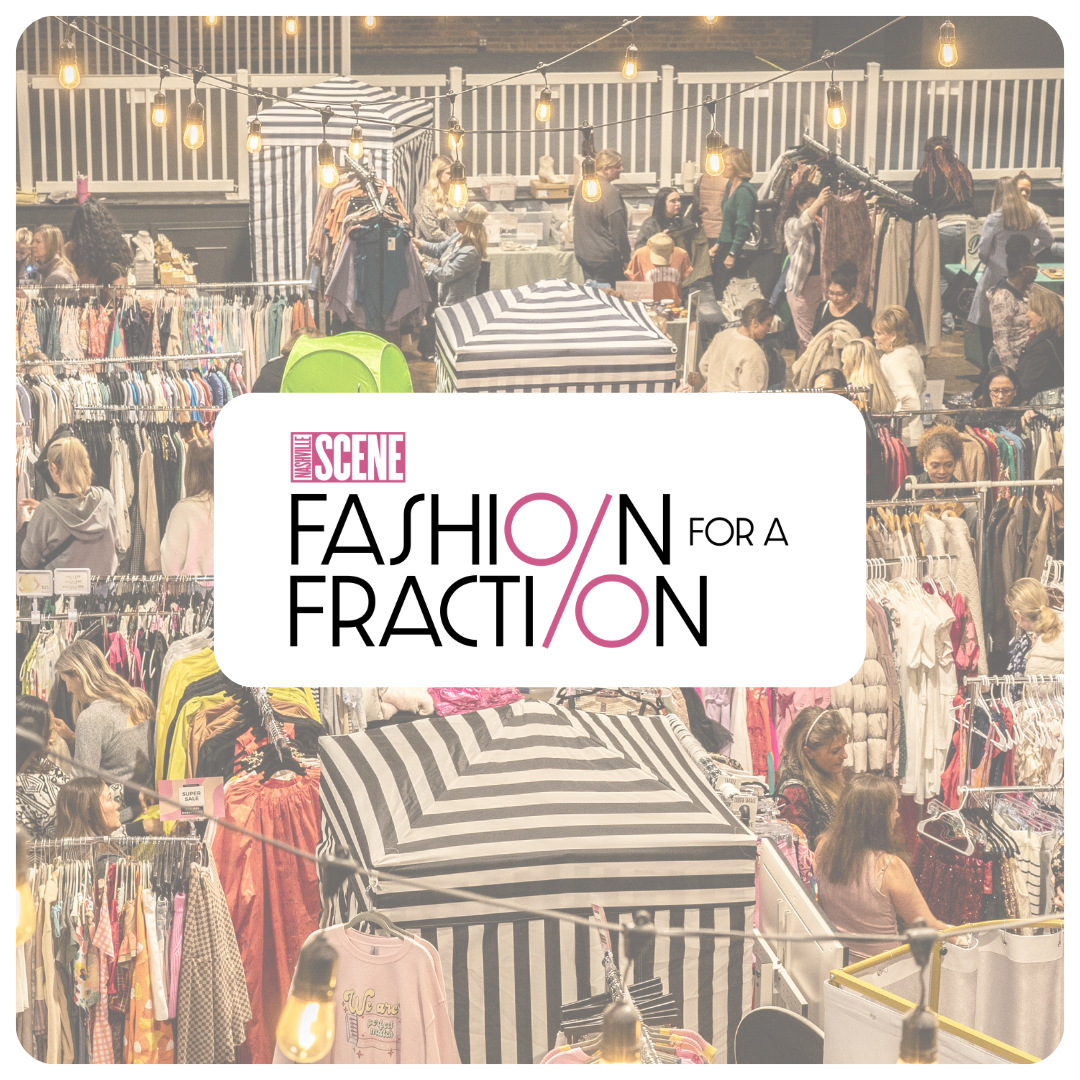 A bustling indoor flea market with racks of clothing, vendors, and shoppers, illuminated with string lights hanging from the ceiling.