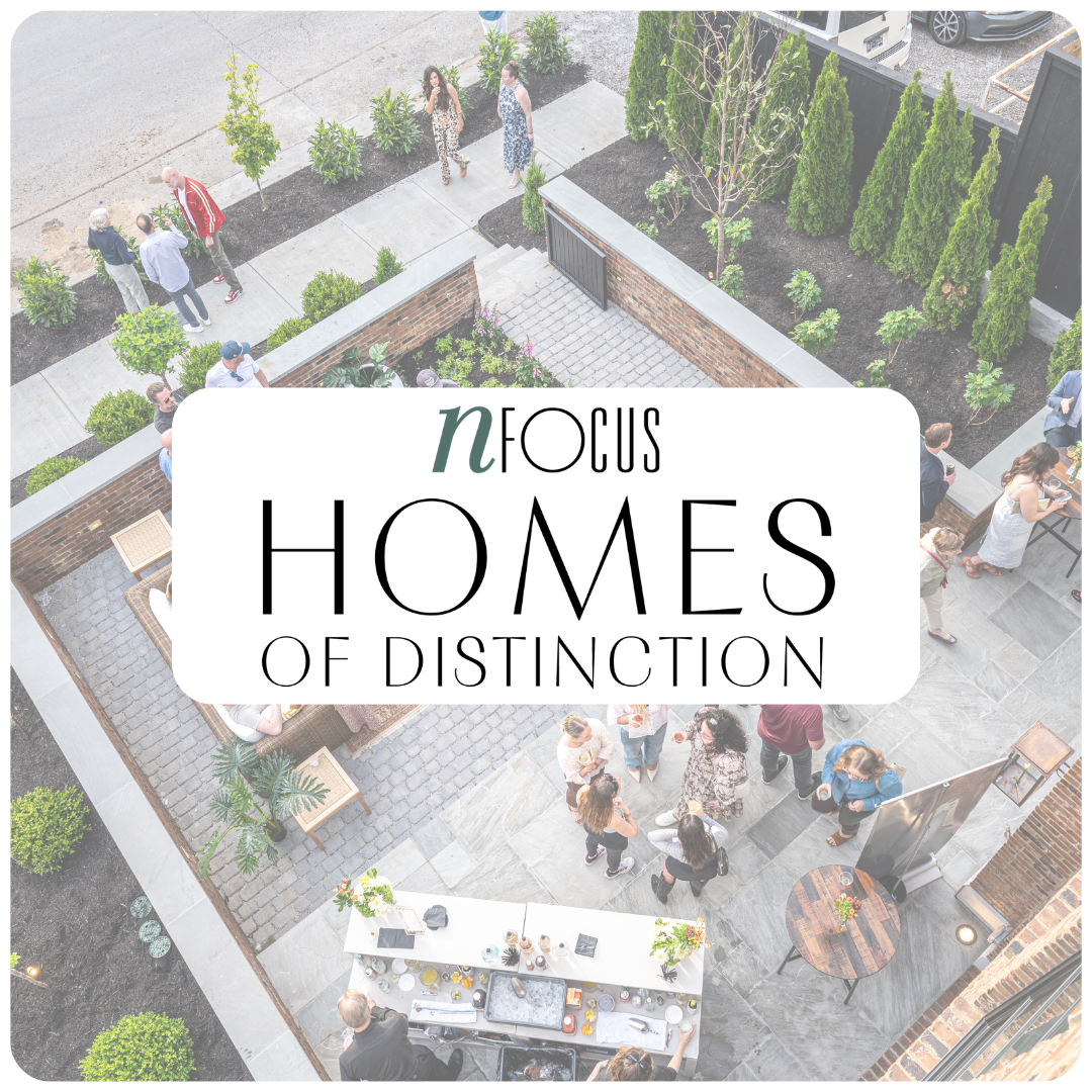 People socializing and mingling in a modern backyard with outdoor seating, plants, and a buffet table, viewed from above.