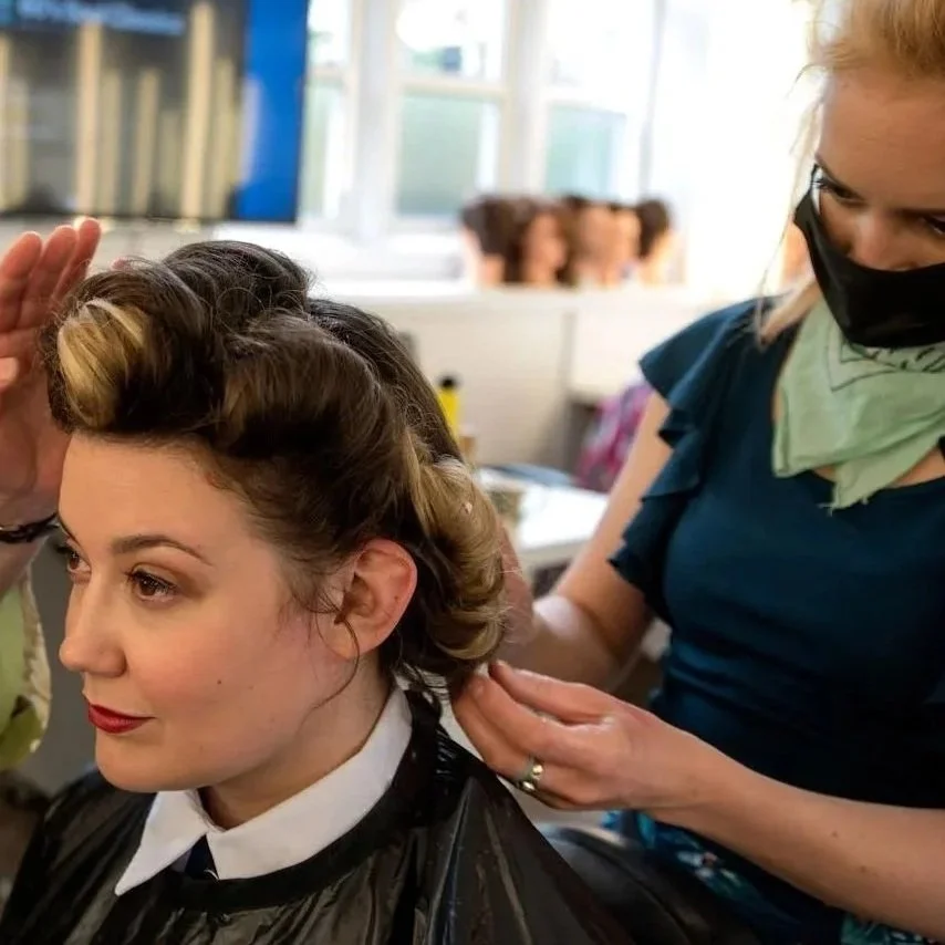 Woman with vintage hair styled for a special occasion gets hairdo from a hairstylist in a salon.