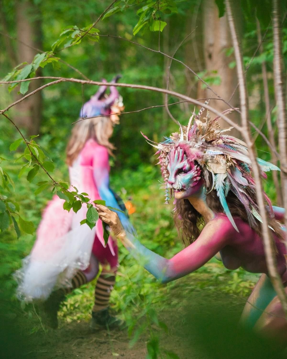 noisily festival uk creature makeup lion lioness is in the woods or forest, she's a performer for hire at events, she is full body painted wearing custom made prosthetics by Painted Peach based in bristol. Pink, blue, gold, green, beautiful, artist