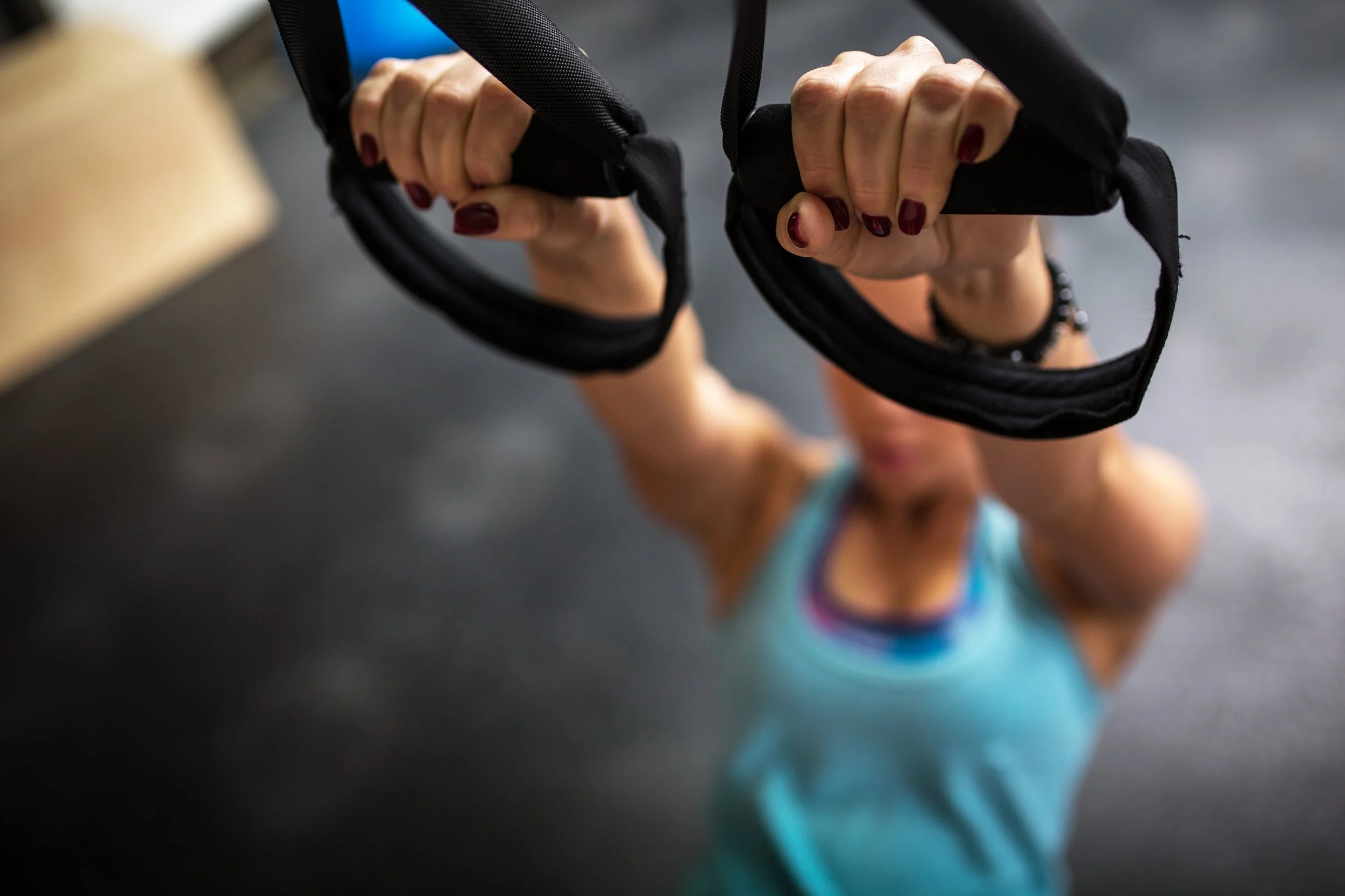 Close-up of a woman gripping gymnastic rings during a workout in a gym.
