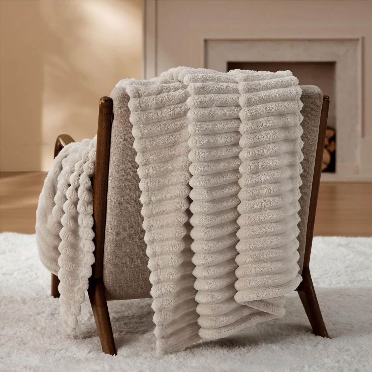 A beige armchair with wooden legs, draped with white plush towels, in a cozy room with a fireplace in the background.