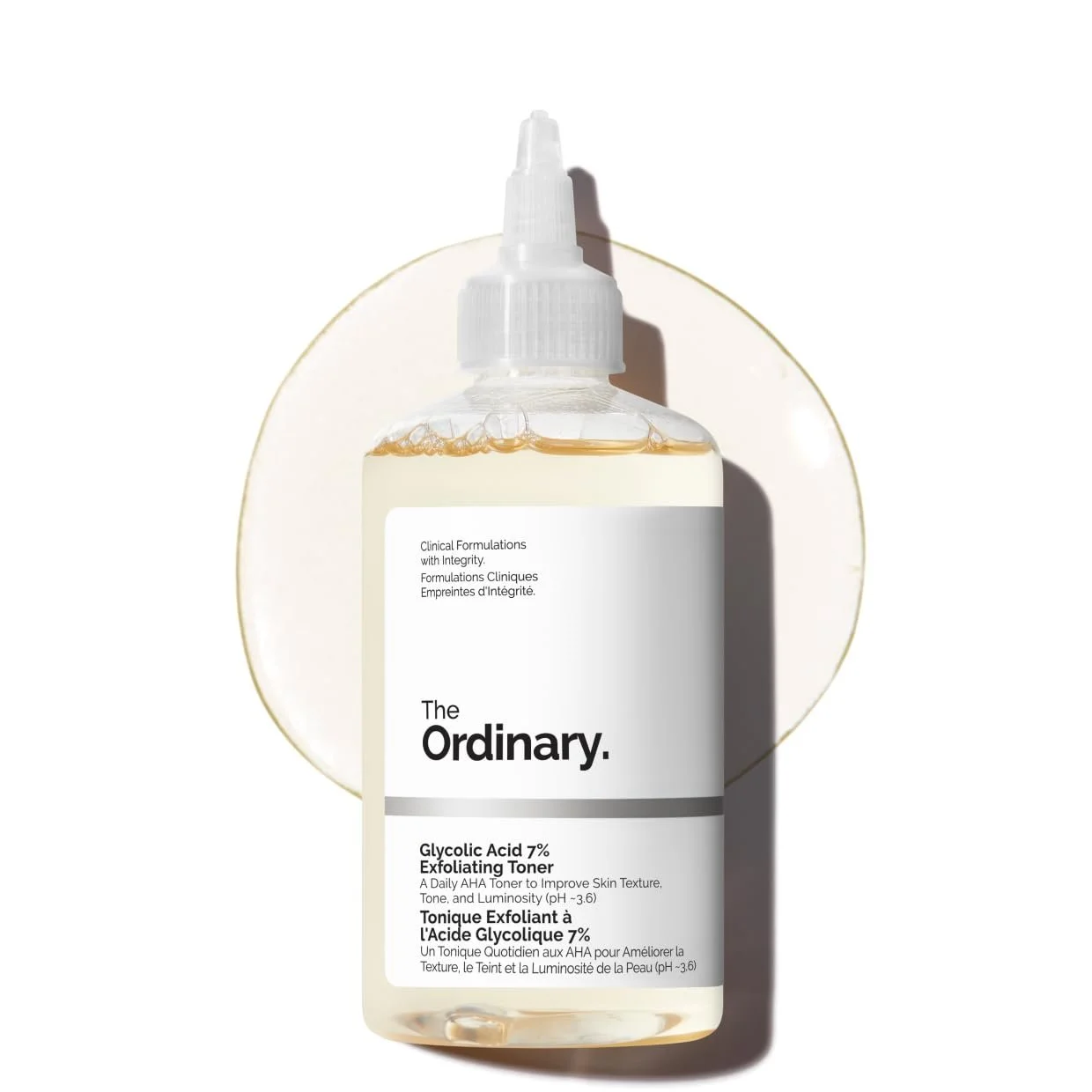 A bottle of The Ordinary Glycolic Acid 7% Exfoliating Toner with a white label, placed on a white surface with a circular white background.