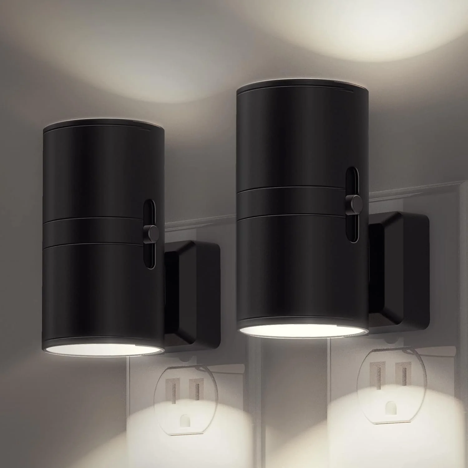 Two black modern wall-mounted cylindrical light fixtures casting light both upwards and downwards.