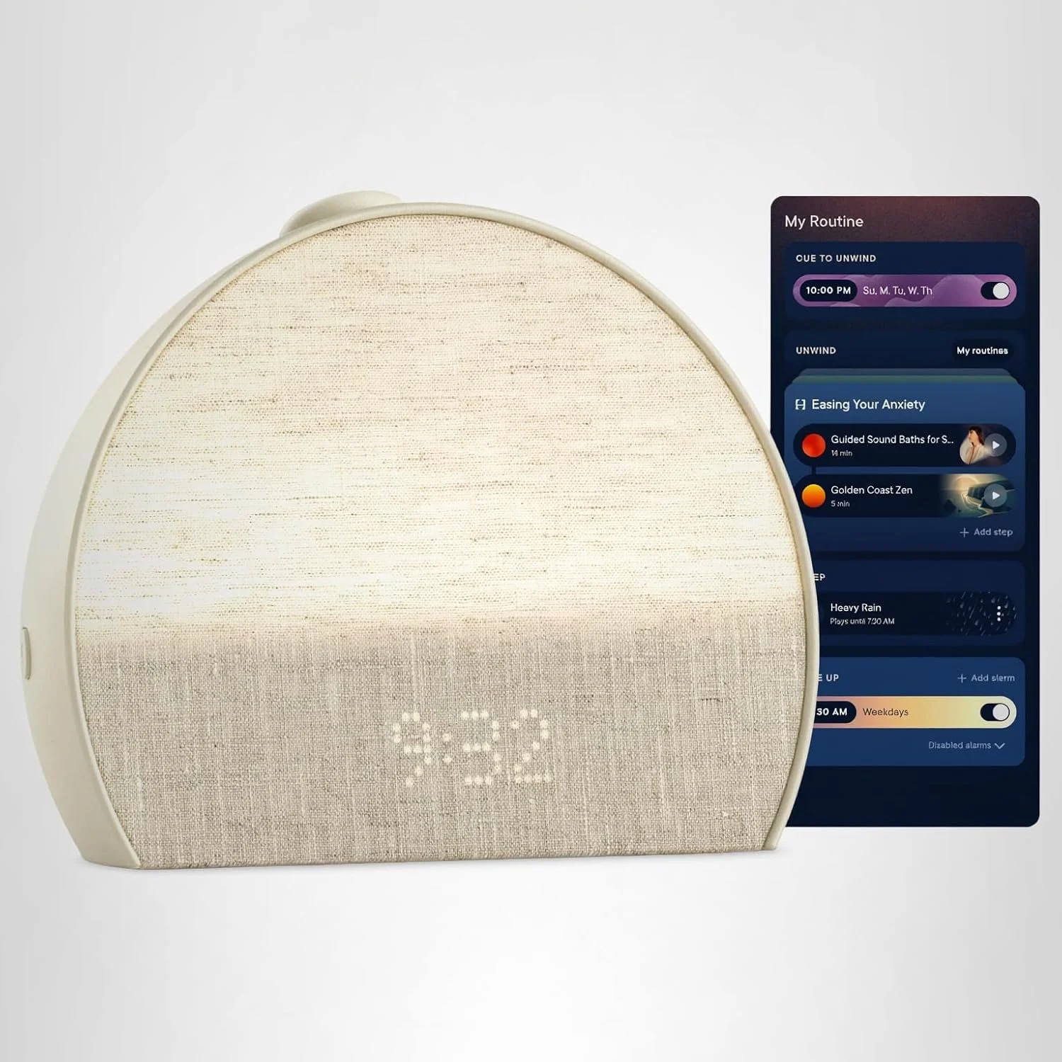 An electronic alarm clock with a fabric-covered front displaying the time 7:32, positioned in front of a smartphone screen showing a sleep and relaxation app with various routines, playlists, and alarm settings.