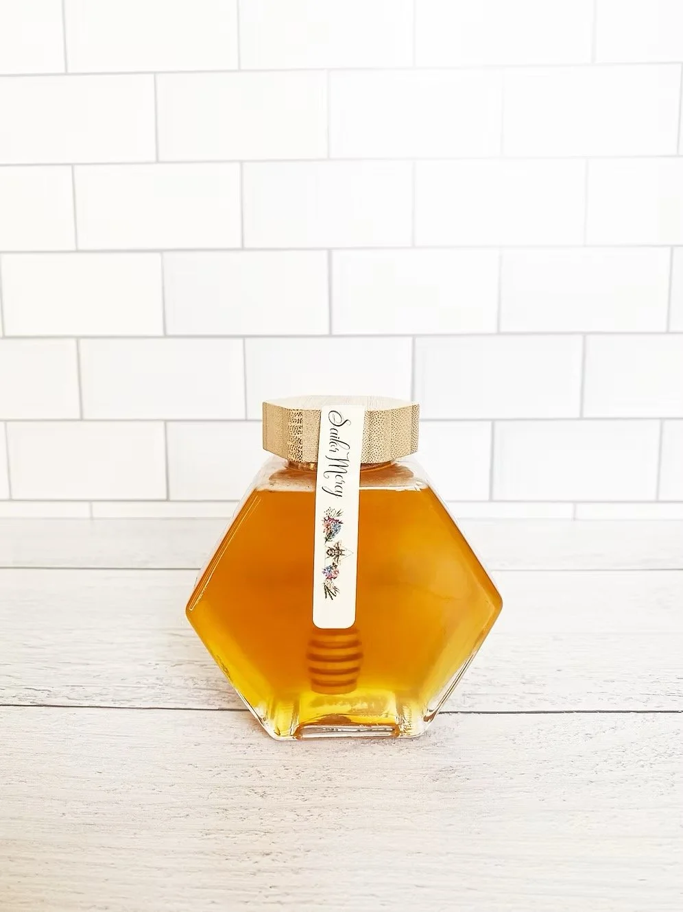 Back view of raw Minnesota honey jar with wooden honey dipper and golden honey