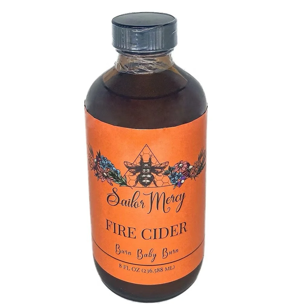 Glass bottle of fire cider with orange label, apple cider vinegar herbal tonic