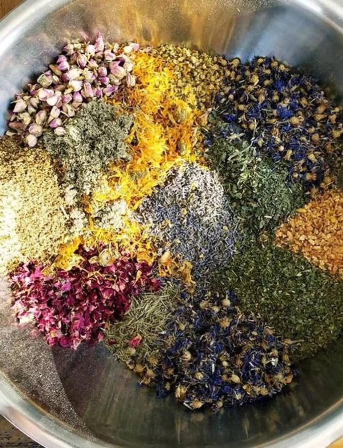 Assorted dried herbs and botanicals used in handcrafted facial toner including flowers, leaves, and natural ingredients