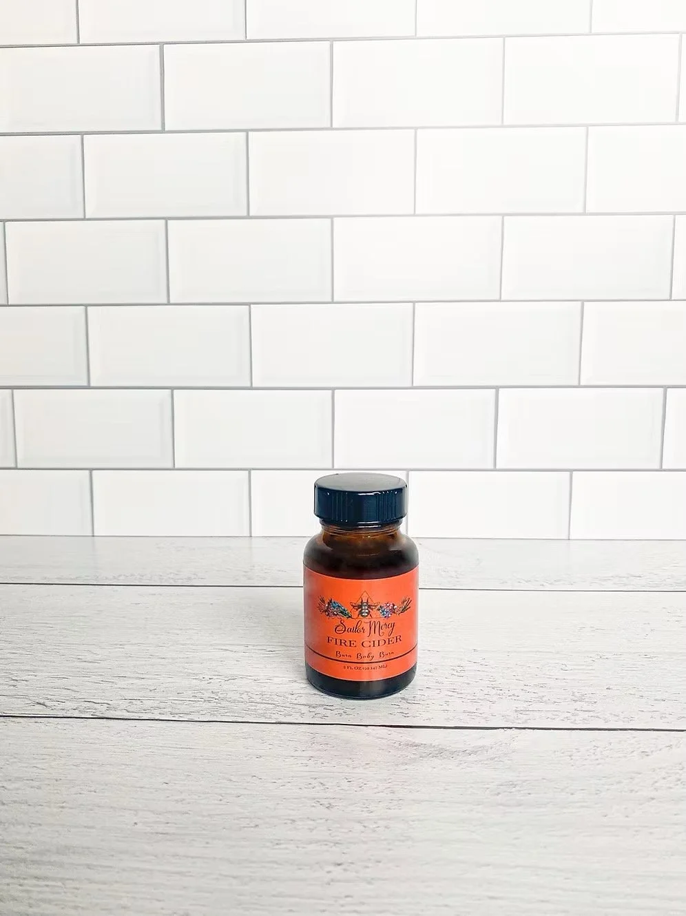Small size fire cider bottle on white tile background for herbal wellness tonic