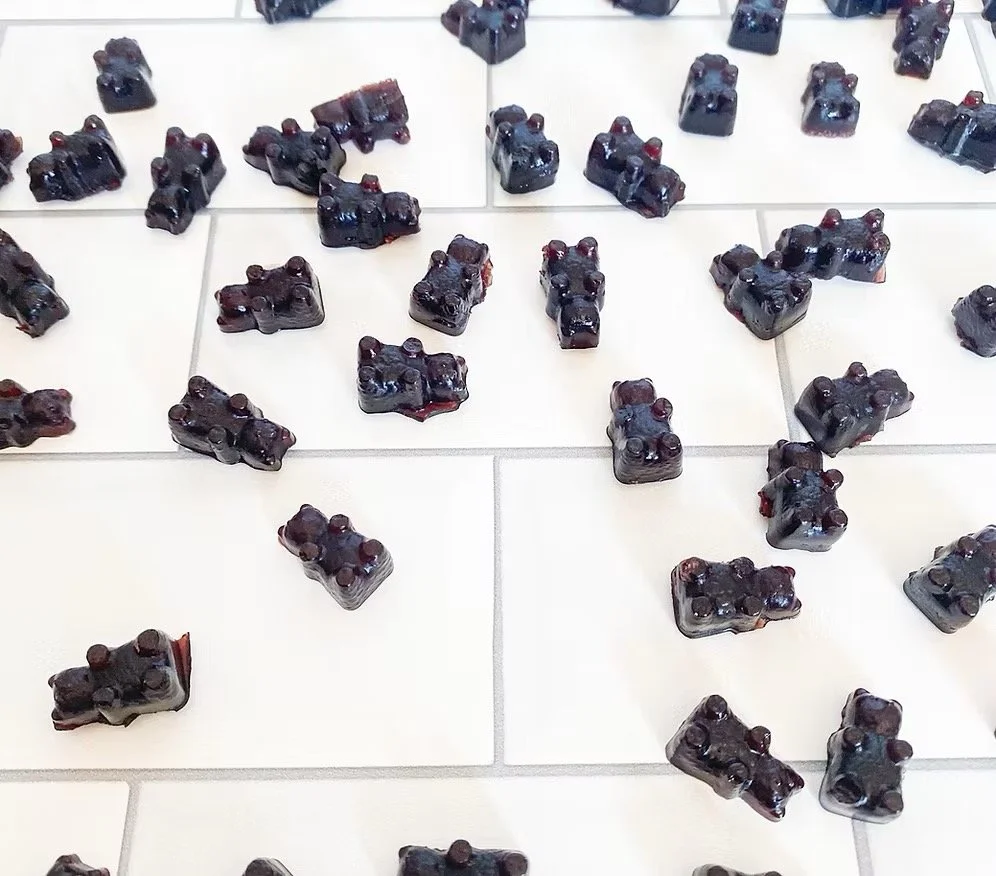 Elderberry gummies shaped like bears spread out on light background