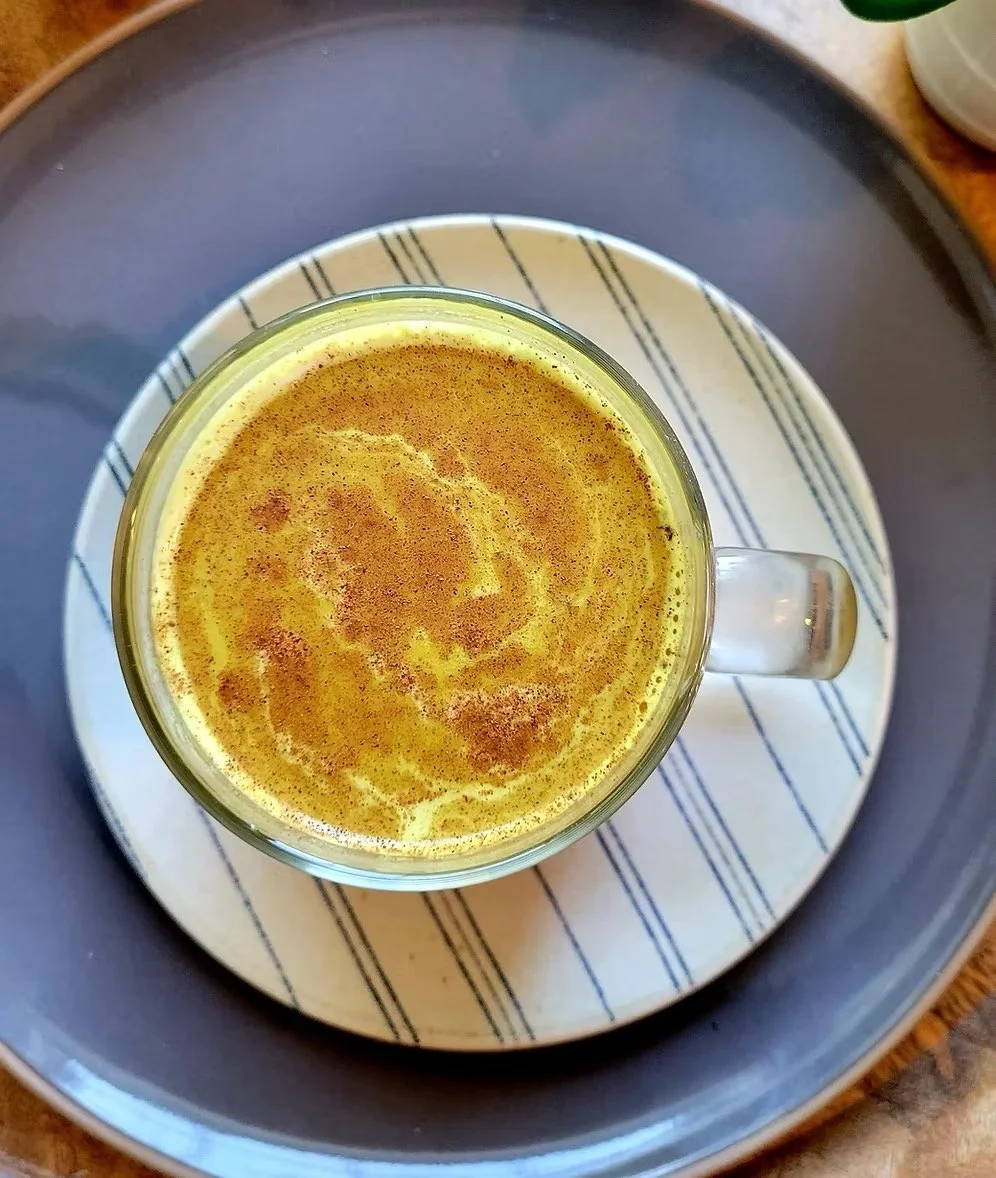 Golden milk latte turmeric drink in glass mug with cinnamon topping in cozy setting