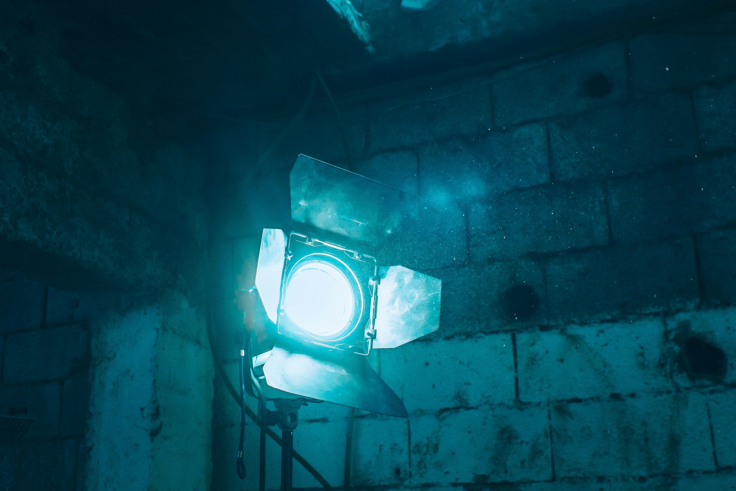 Studio light shining brightly on a brick wall, creating a glow with visible dust particles in the air.