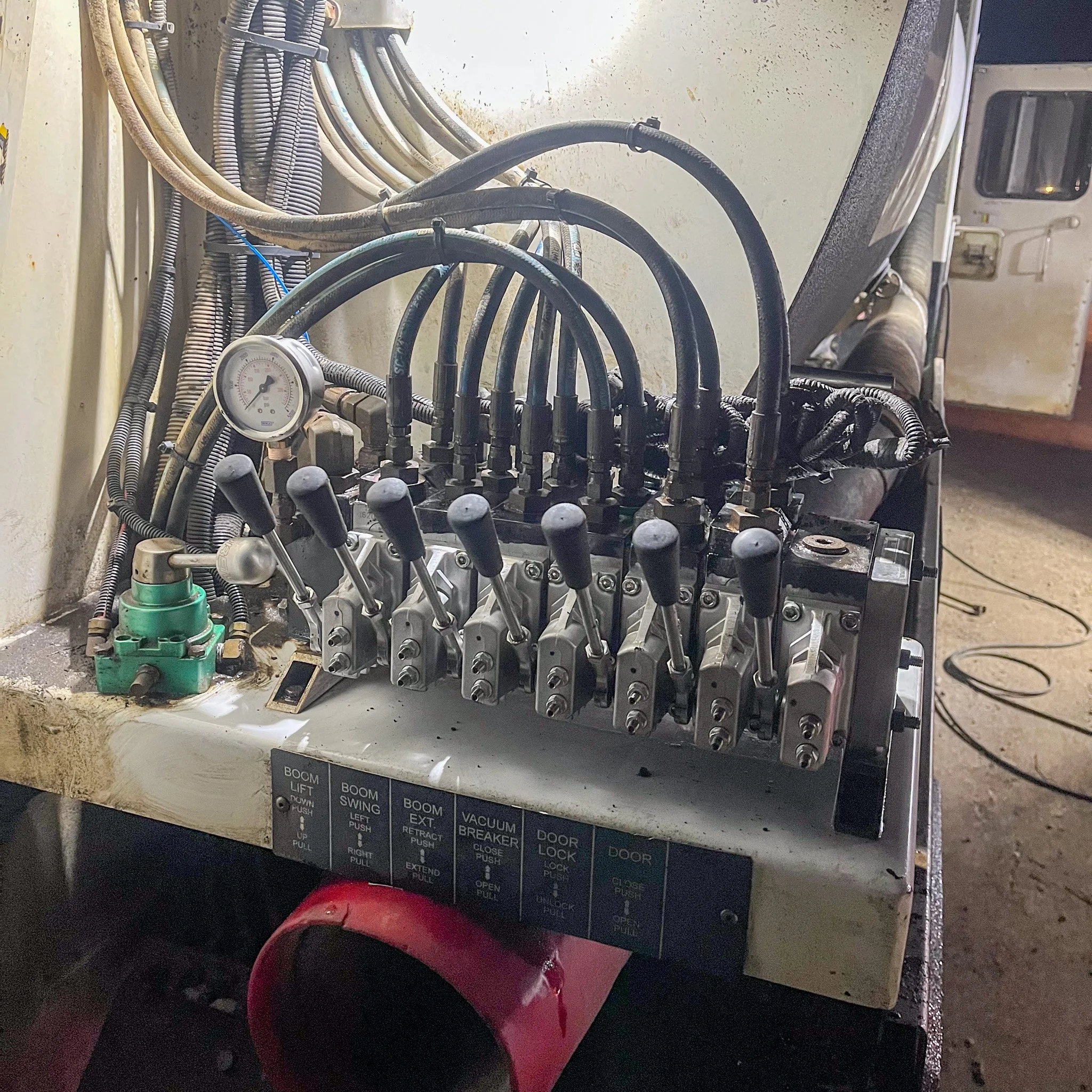 A control panel with multiple levers, switches, and gauges, connected to various pipes and wires in an industrial setting.